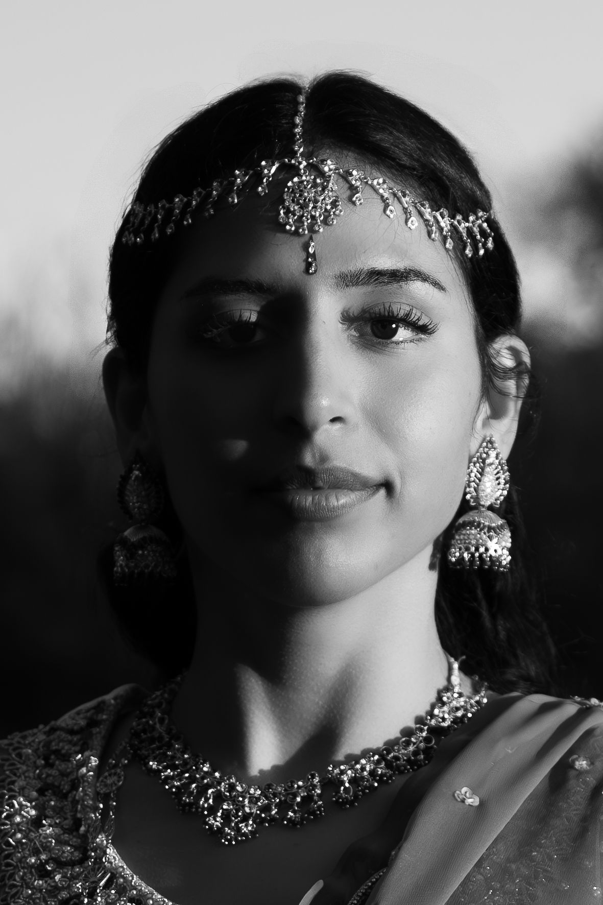 Black and white portrait of Indian bride wearing traditional jewelry and maang tikka.