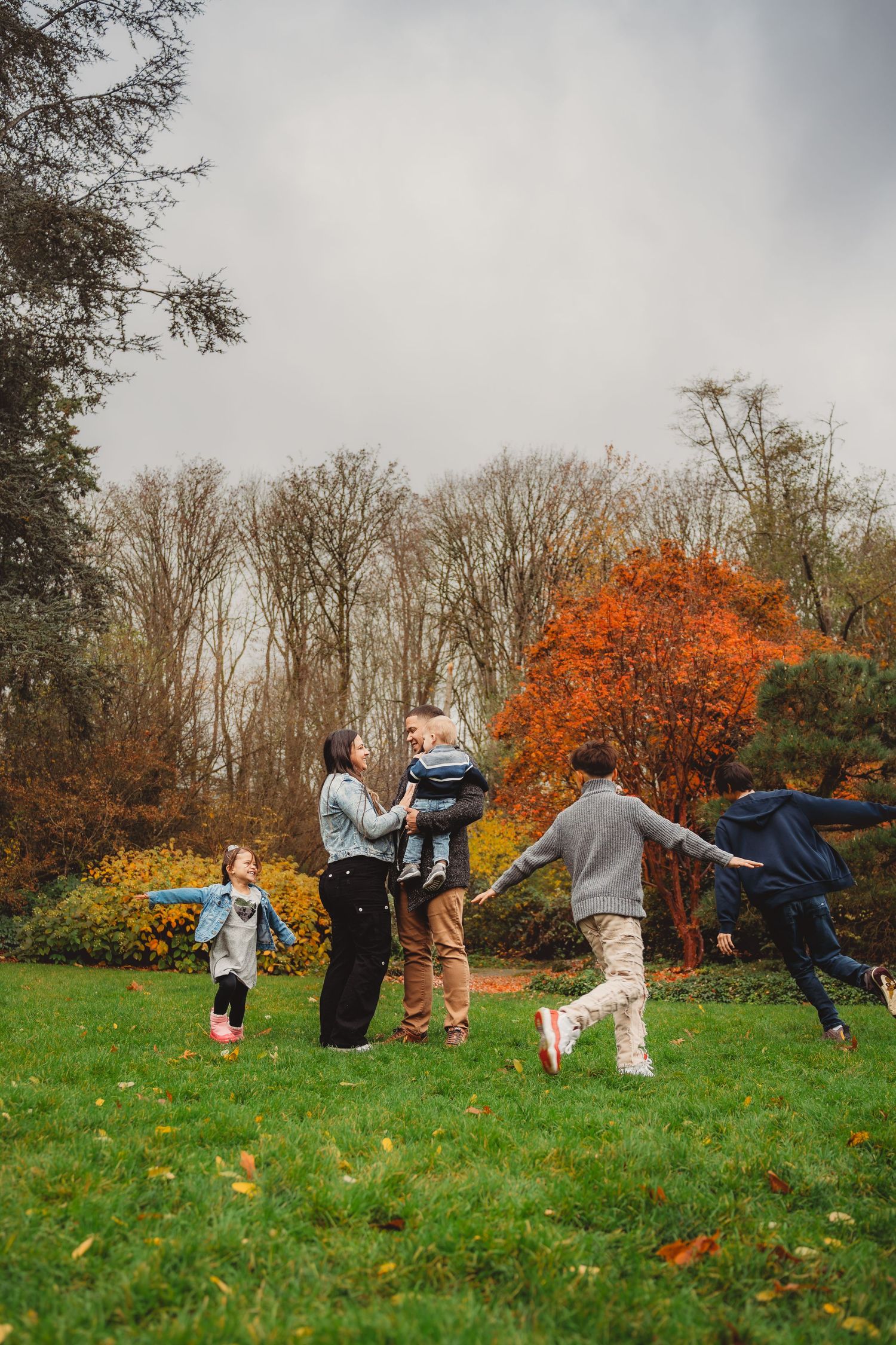 Joyful family playing together on green grass in colorful autumn park. Japanese garden Seattle