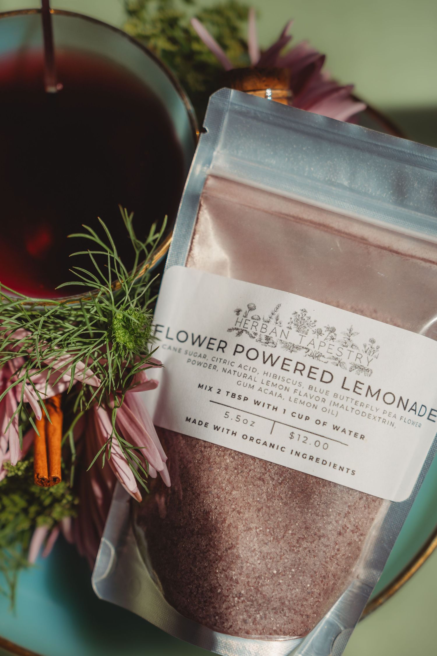 Flower Powered Lemonade organic drink mix packet surrounded by fresh herbs and echinacea flowers. South Carolina Summerville