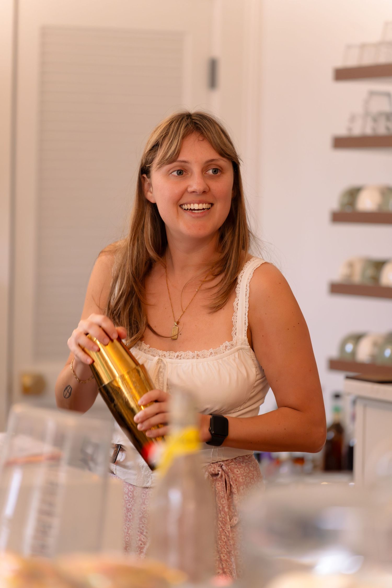 Smiling woman holding wine bottle in bright modern kitchen interior.