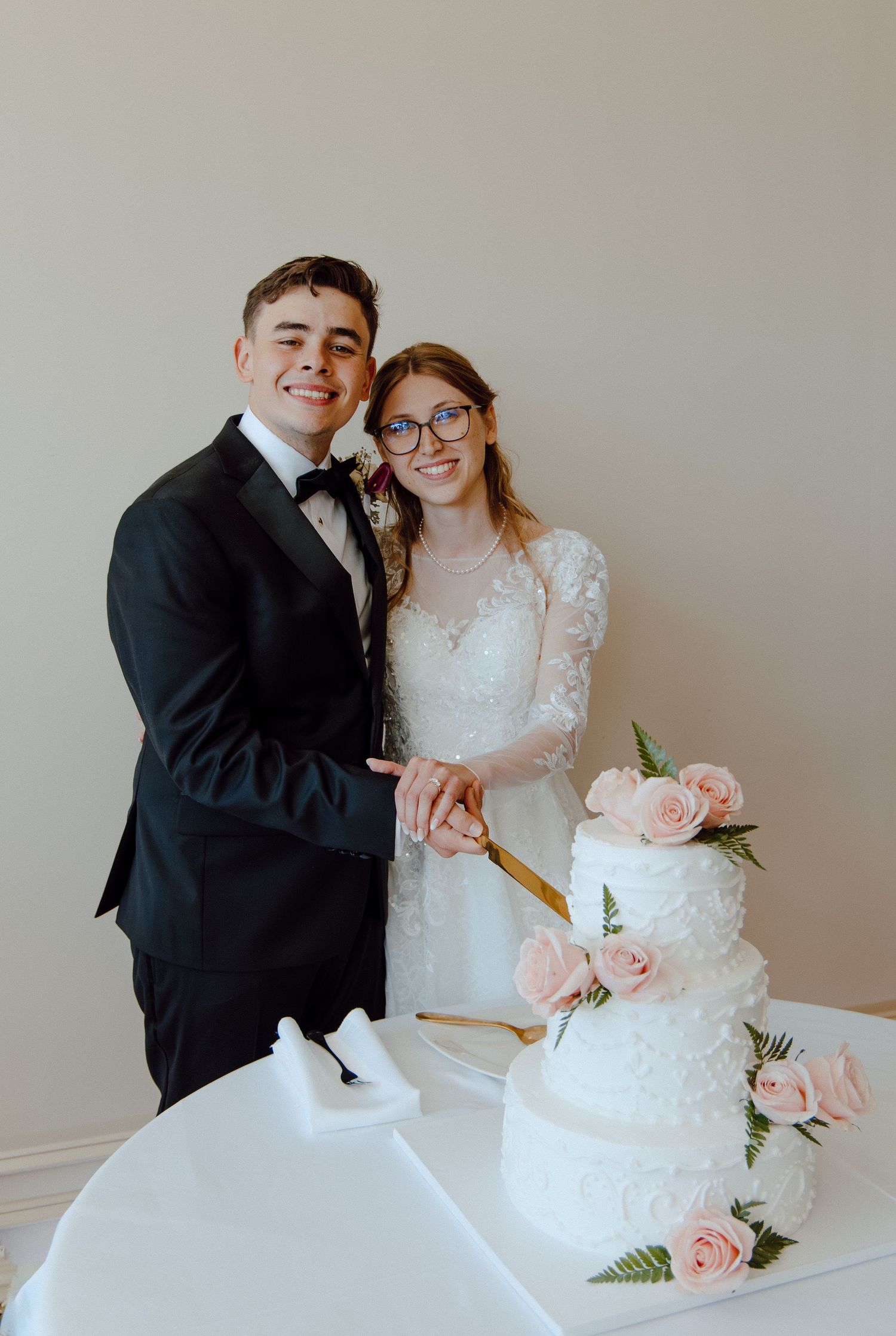 Couple cutting their wedding cake together, celebrating unity and joy with classic décor and a timeless, elegant reception moment.