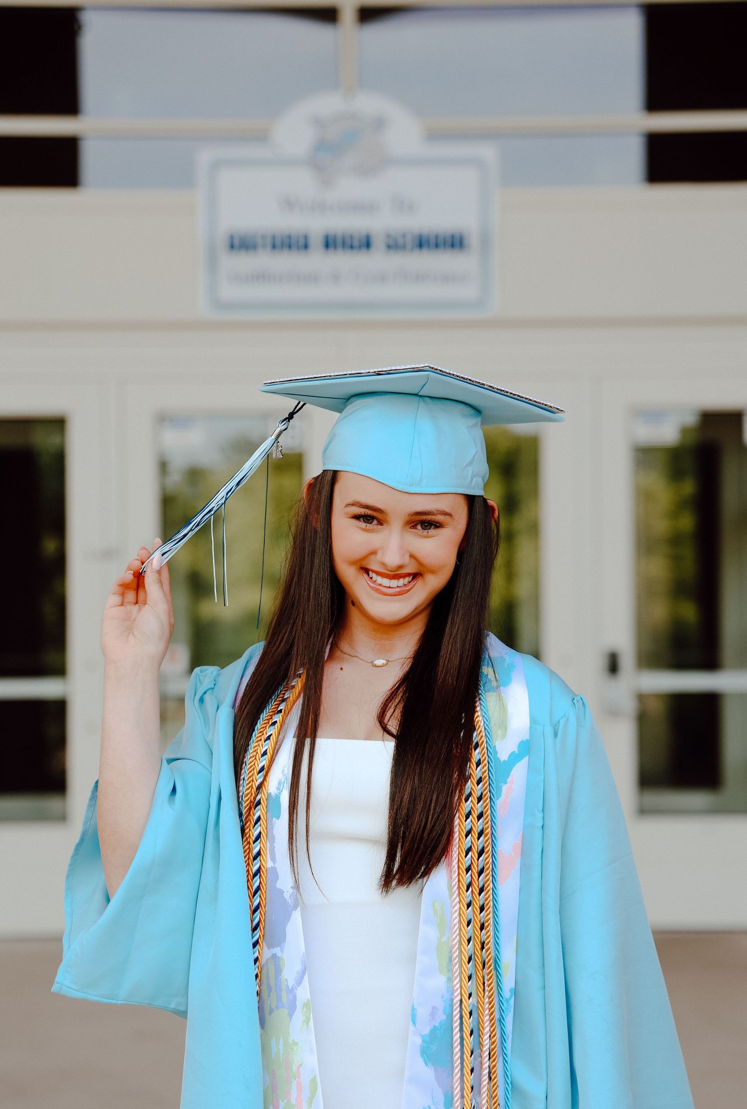Oxford High School senior celebrating graduation in cap and gown, smiling proudly with honor cords and bright natural light at the school