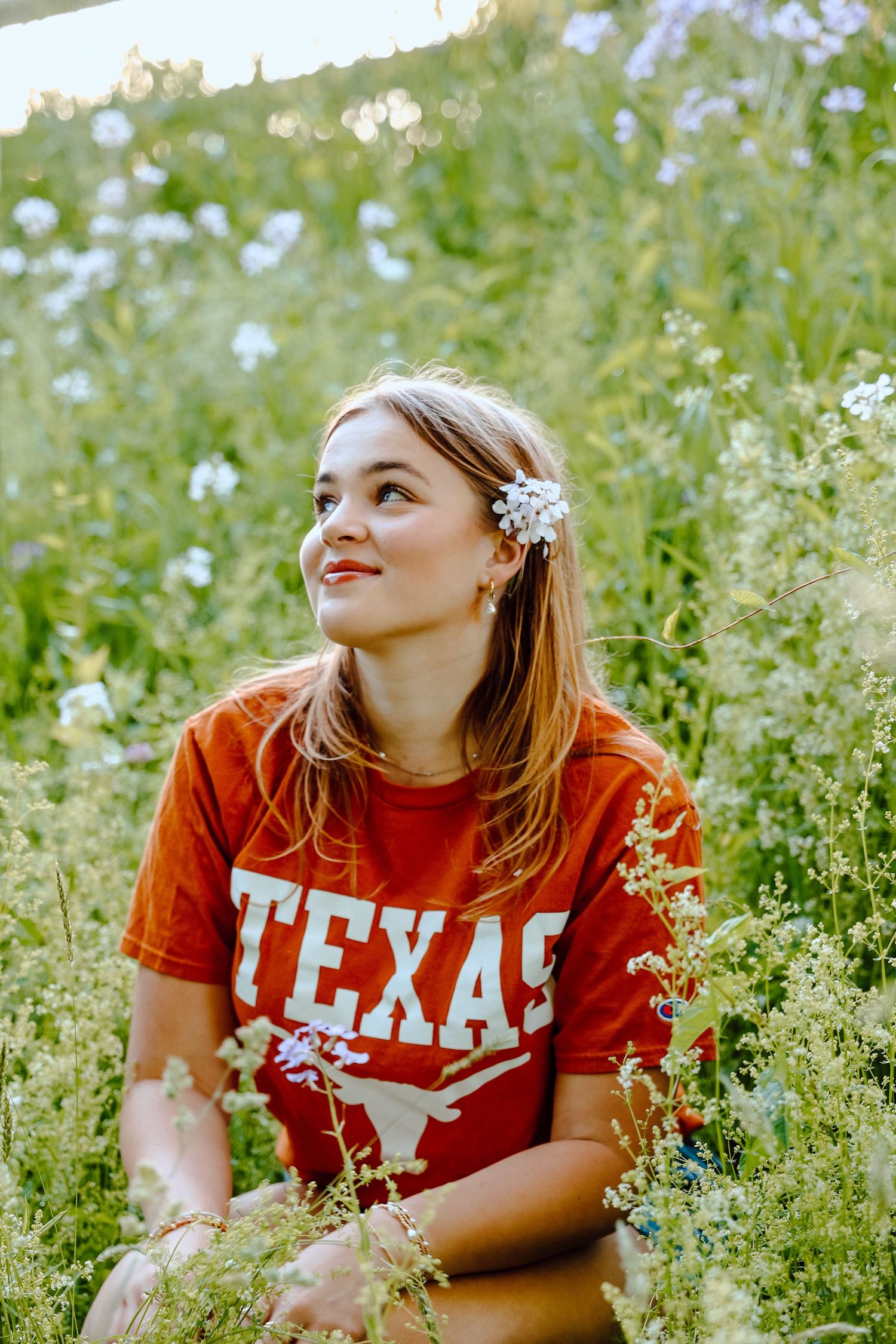 Senior portrait in wildflowers featuring a future University of Texas student, captured in soft natural light with proud Texas spirit