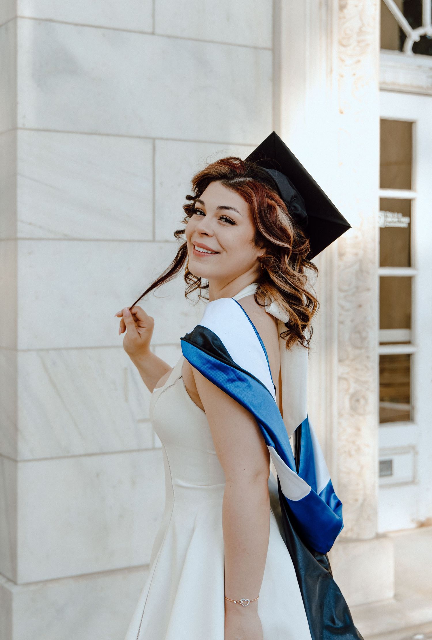 CCSU graduation portrait featuring senior in cap and stole, celebrating achievement with bright, elegant style against campus architecture