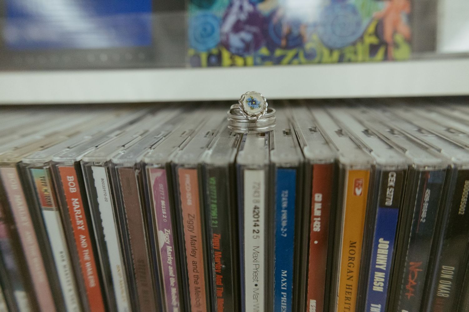 A collection of music CDs lined up on a wooden shelf.
