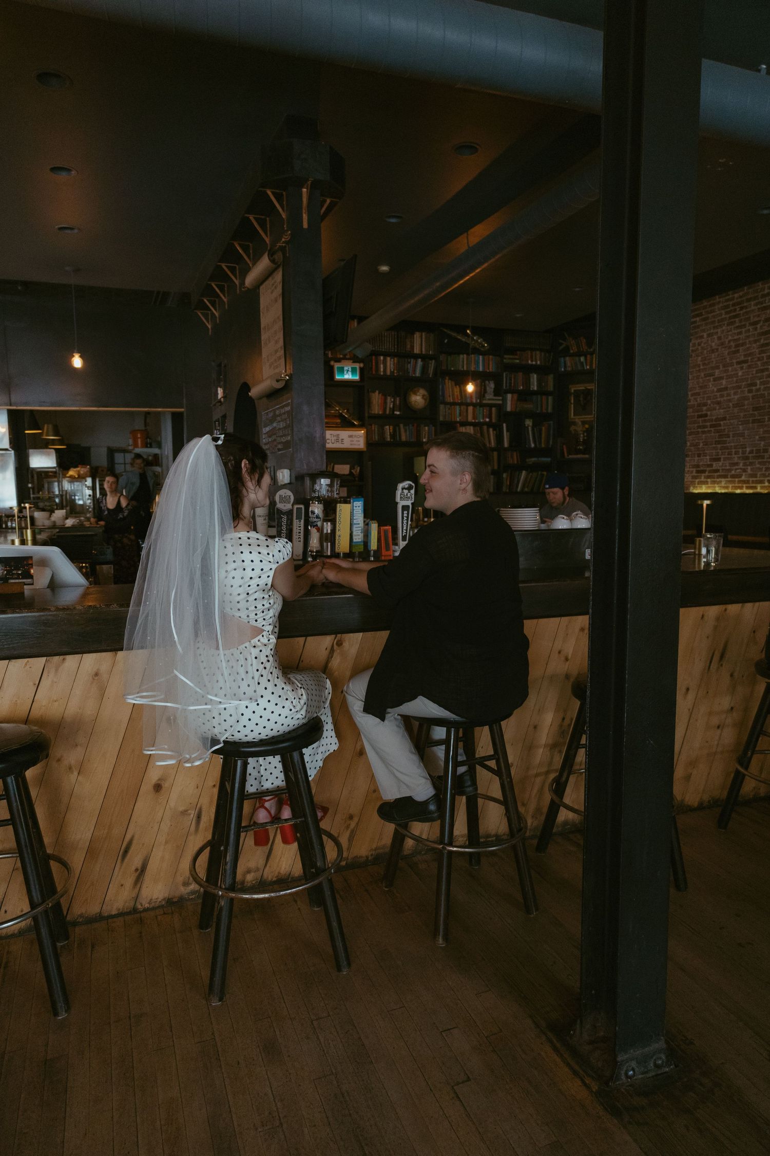 Cozy bar interior with wooden paneling and bookshelves creating an intimate atmosphere.
