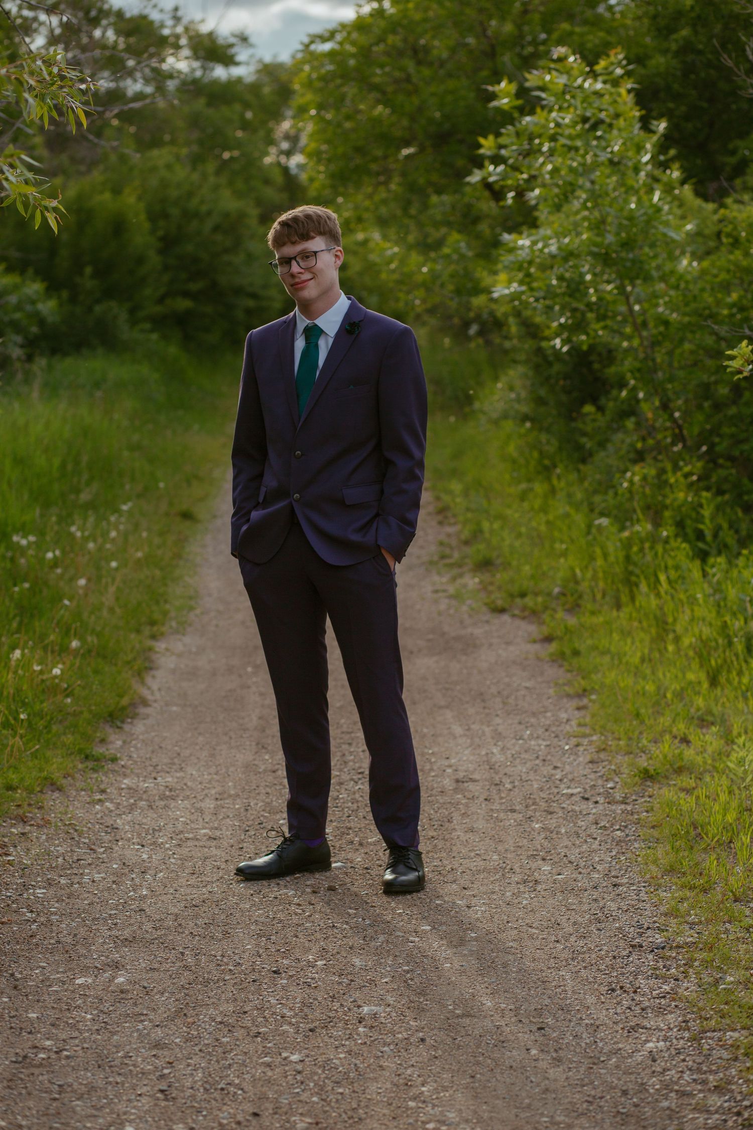 A formal portrait session on a gravel path surrounded by greenery.