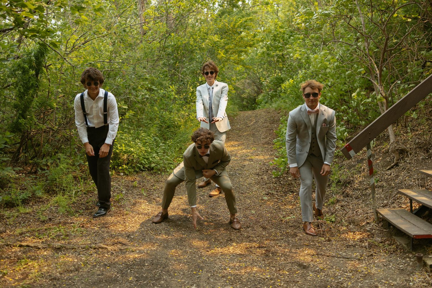Playful group poses on dirt path surrounded by green summer foliage.