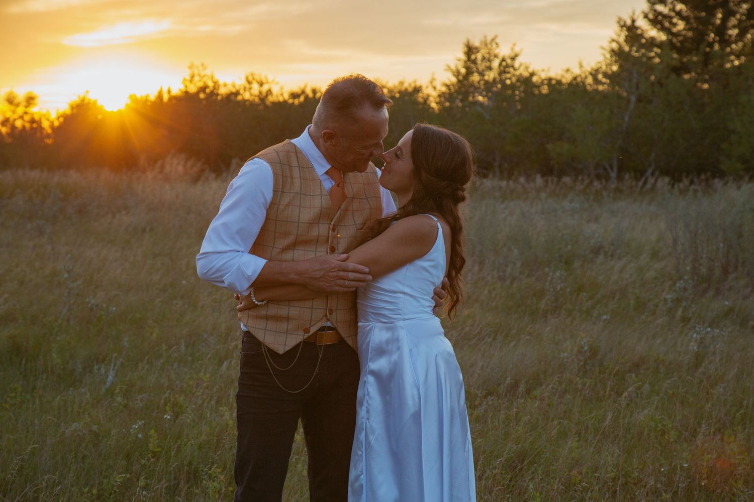 Romantic sunset dance in a grassy meadow with warm golden lighting.