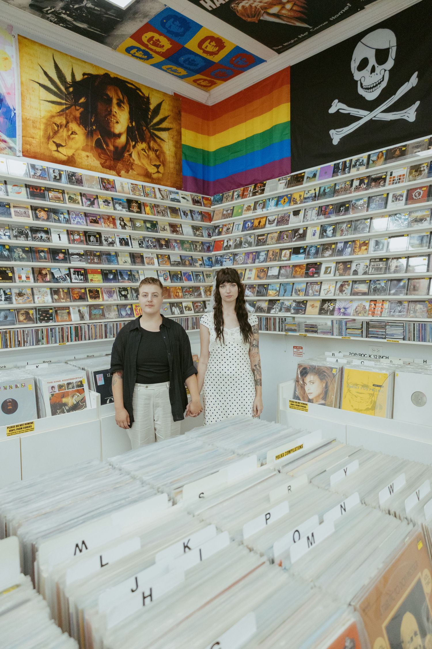 Interior of a record store with white display bins and colorful posters on the walls.