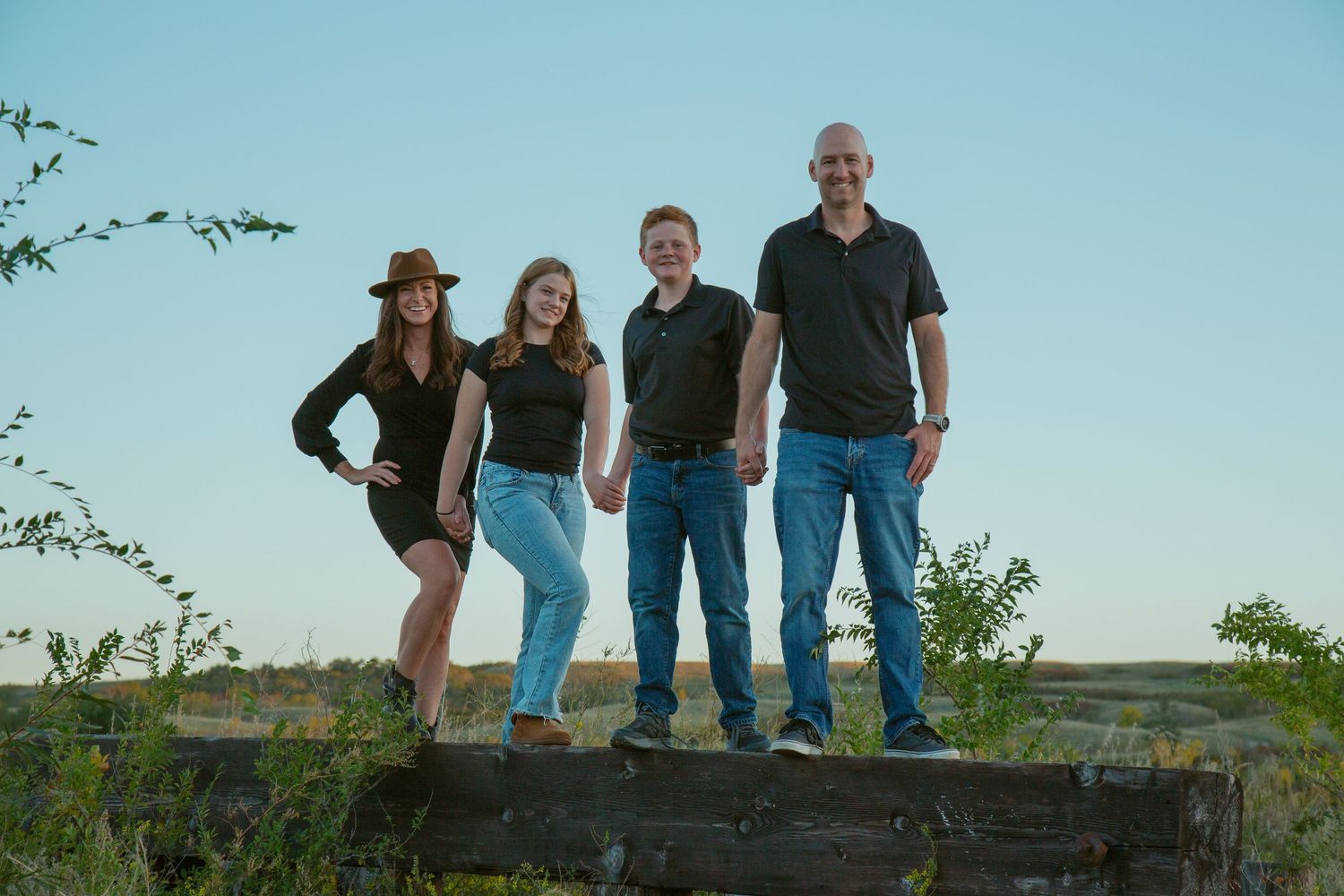 Group standing on a rocky shoreline with boats visible in the background.