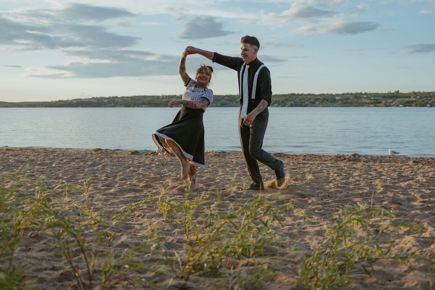 A couple enjoys a playful moment together on a sandy beach at sunset.