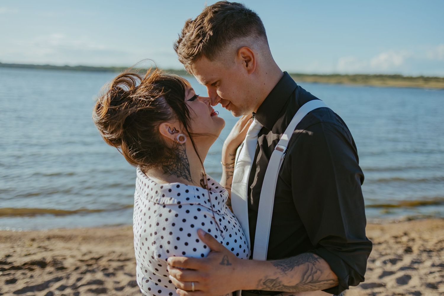 Romantic couple embracing on a beach during a sunny day.