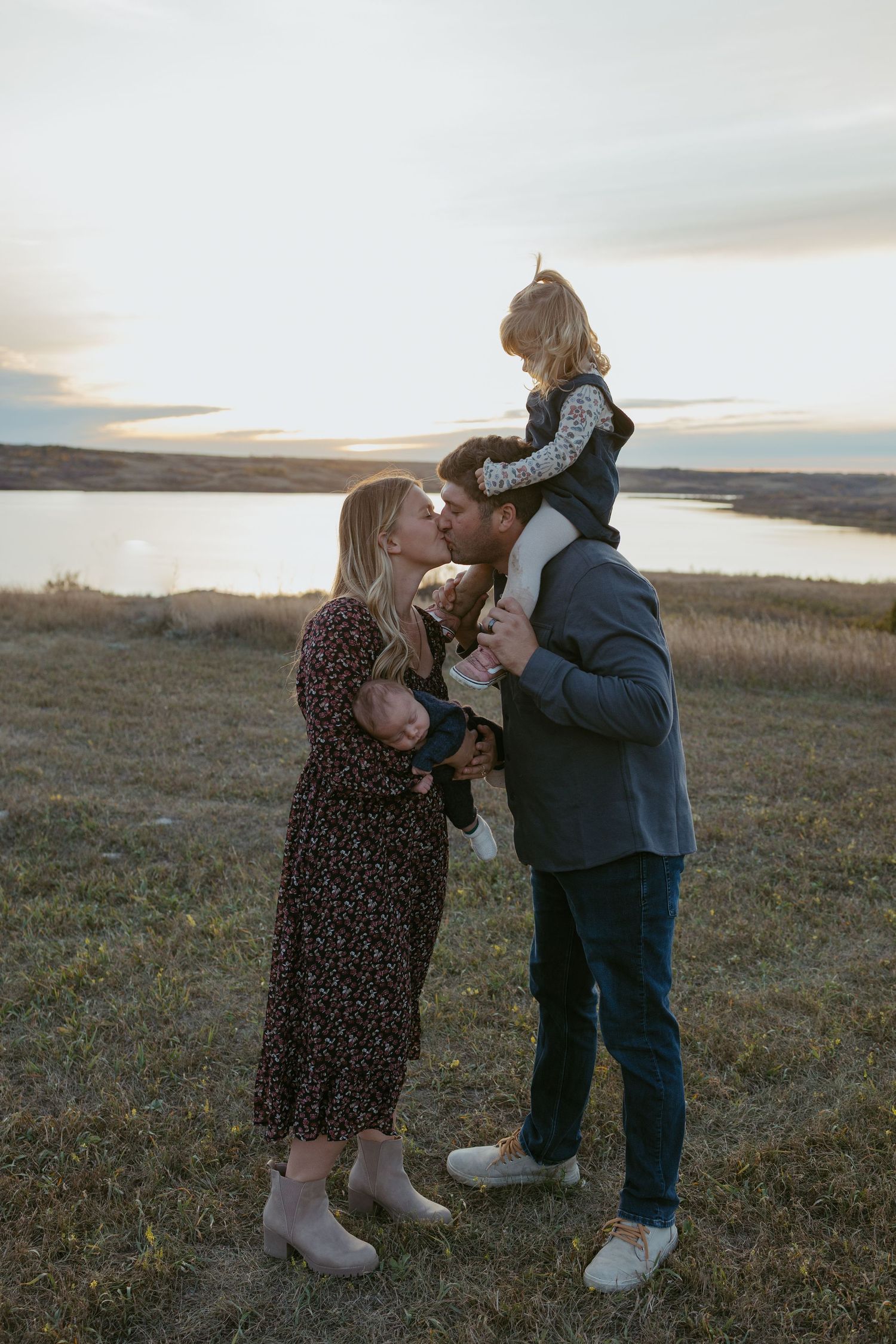 Couple sharing an intimate moment together on a grassy hillside during sunset.