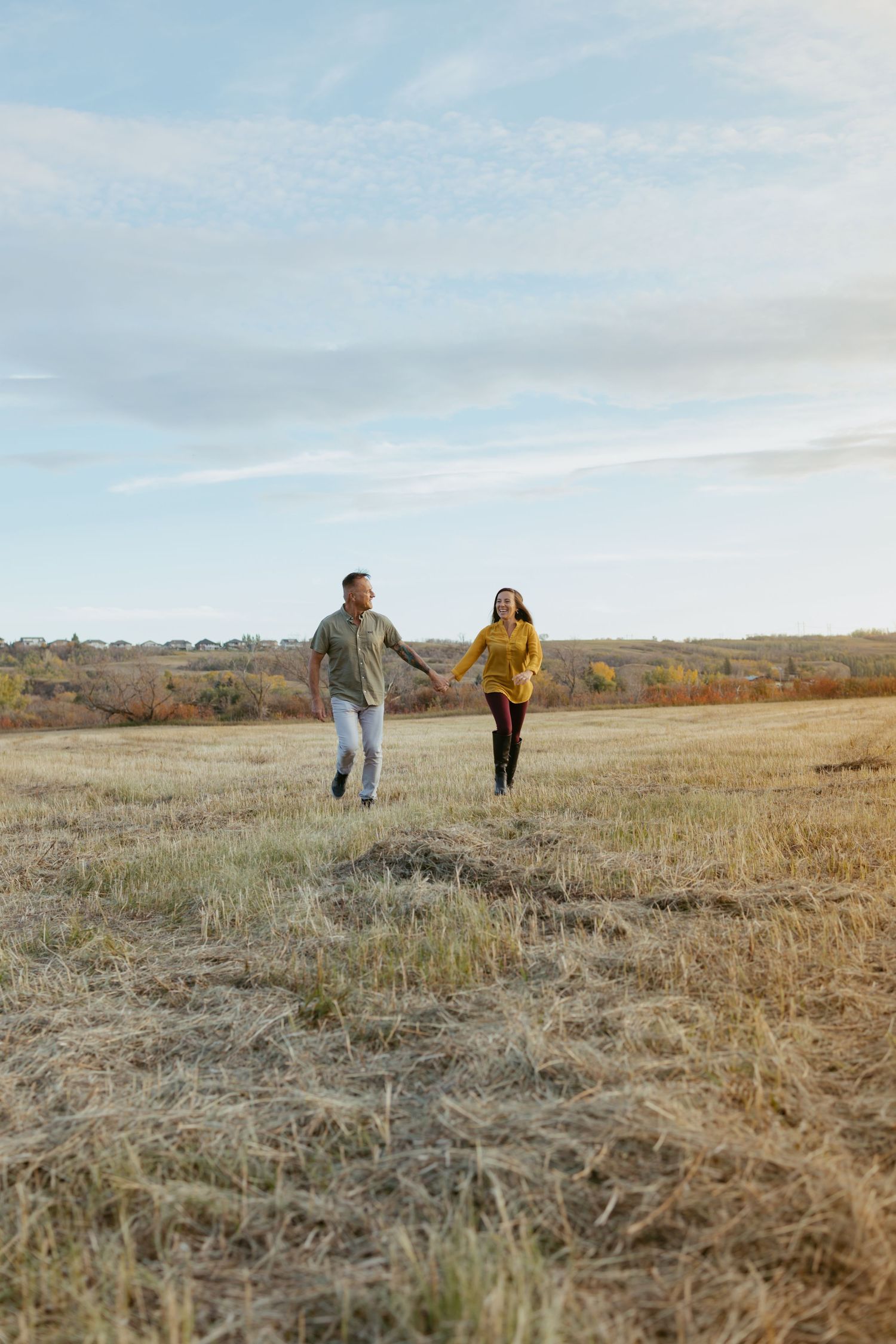 Two figures walking through a golden autumn field with distant hills in the background.