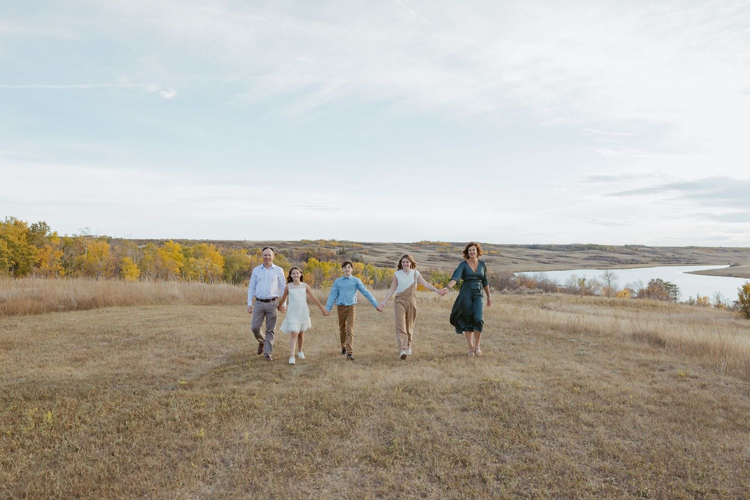 Group exploring a scenic prairie landscape with rolling hills and autumn colors at sunset.