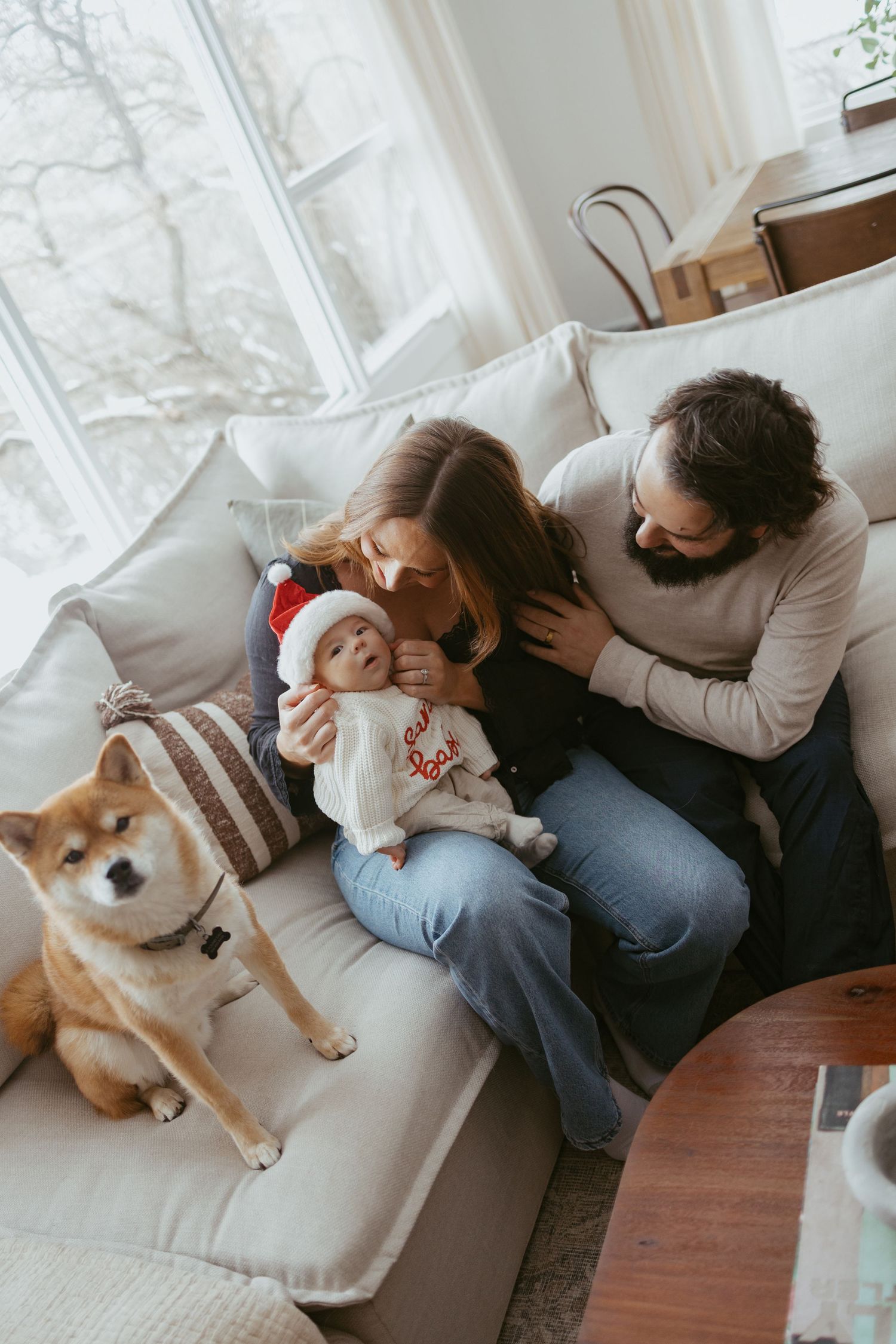 Family relaxing on white couch with their Shiba Inu dog in a bright modern living room.
