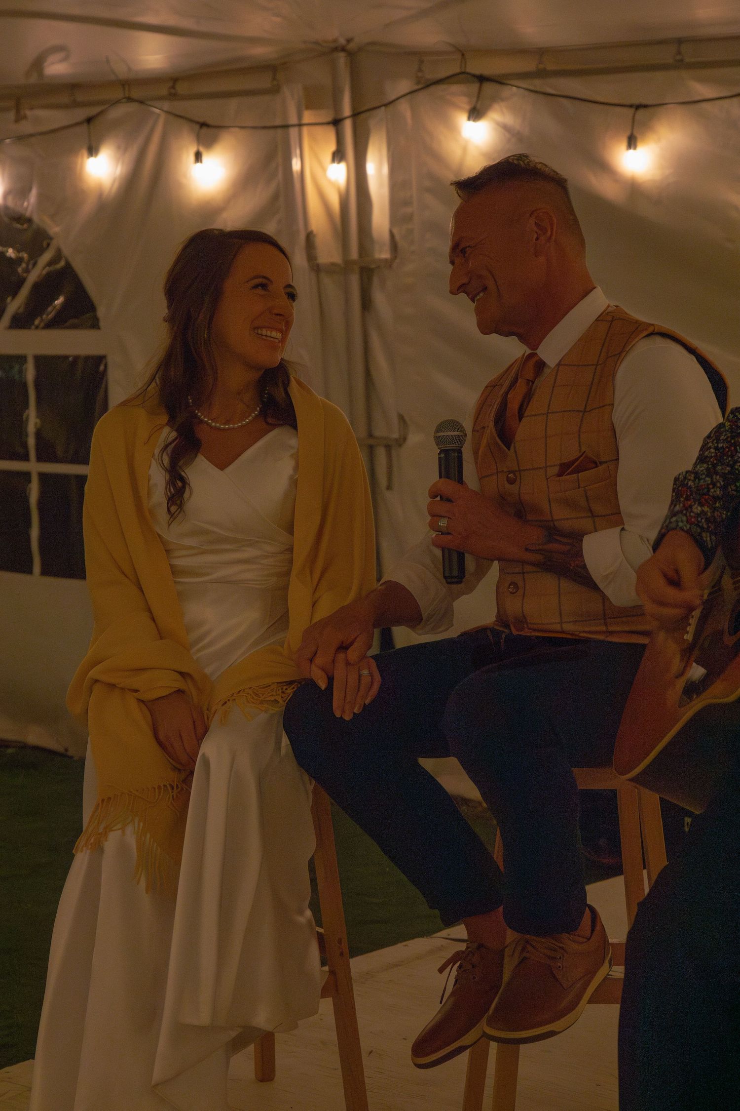 A couple shares a tender moment on a swing at an evening outdoor event.