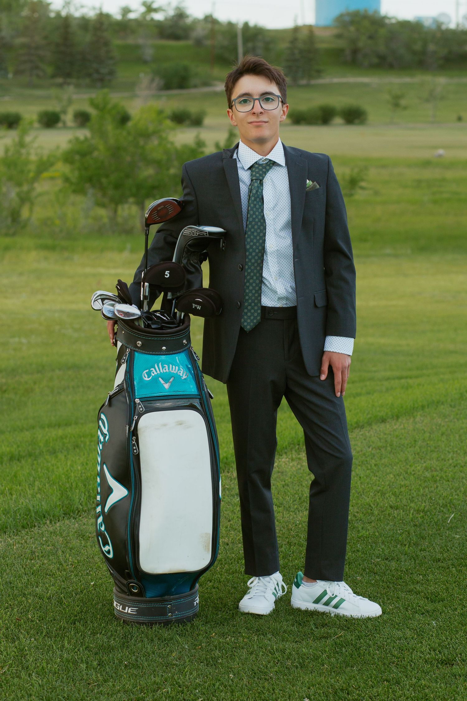 A golf bag and formal attire photographed on green grass.