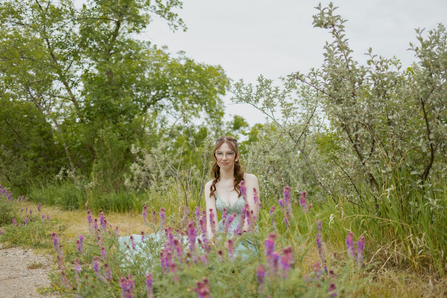 Beautiful wildflowers bloom along natural pathway with trees in background.