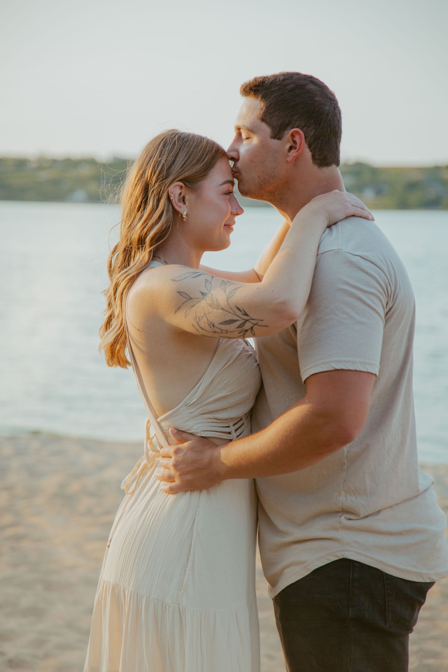 A tender moment between a couple embracing on a beach at sunset.