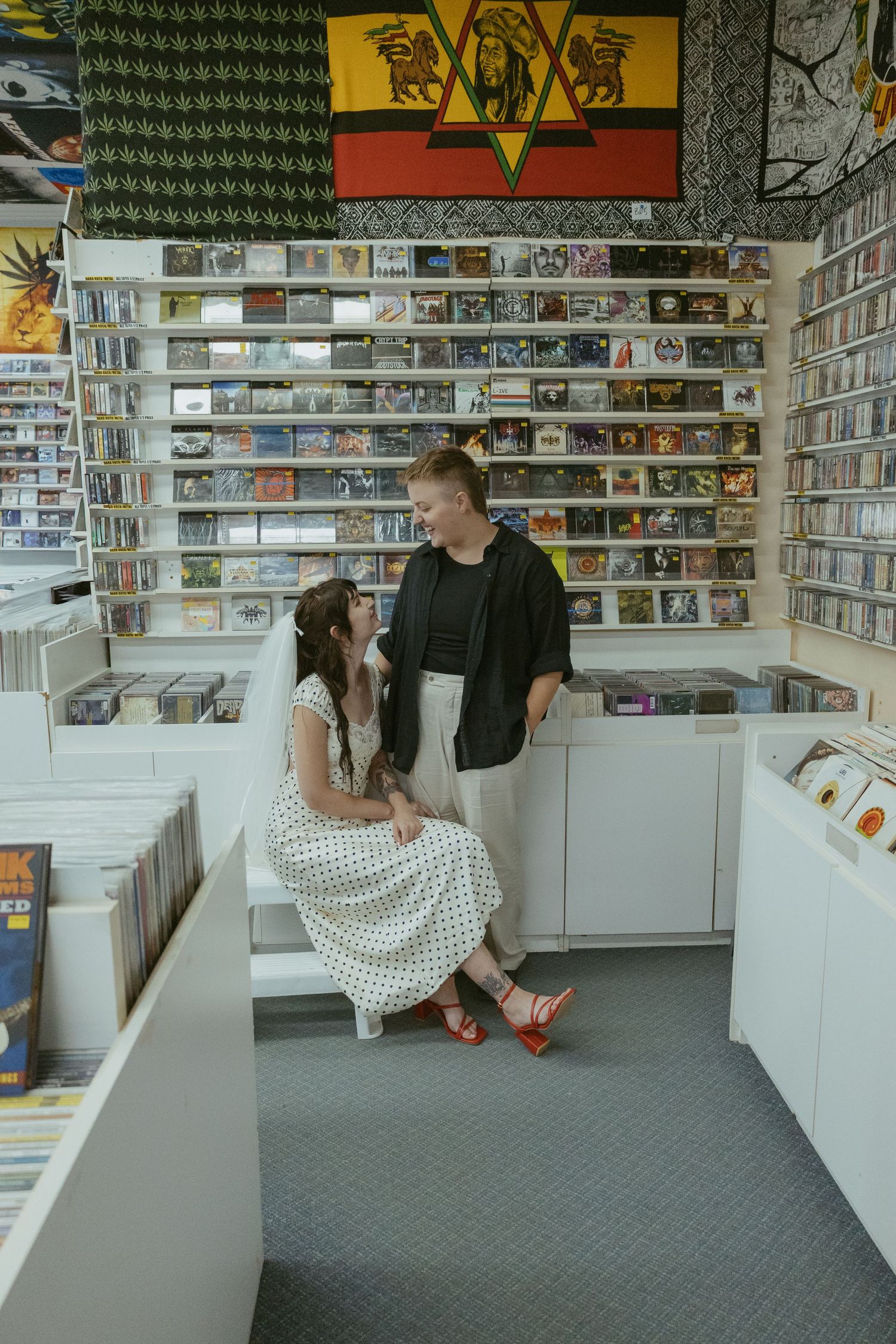 Couple browsing through a record store with walls lined with CDs and posters.