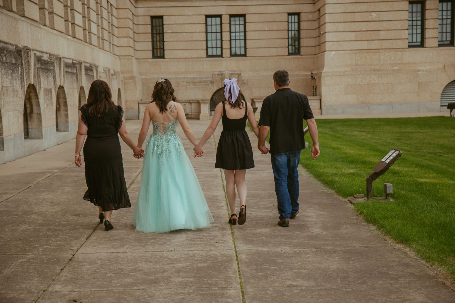 Group walking together on pathway near classic stone building architecture.