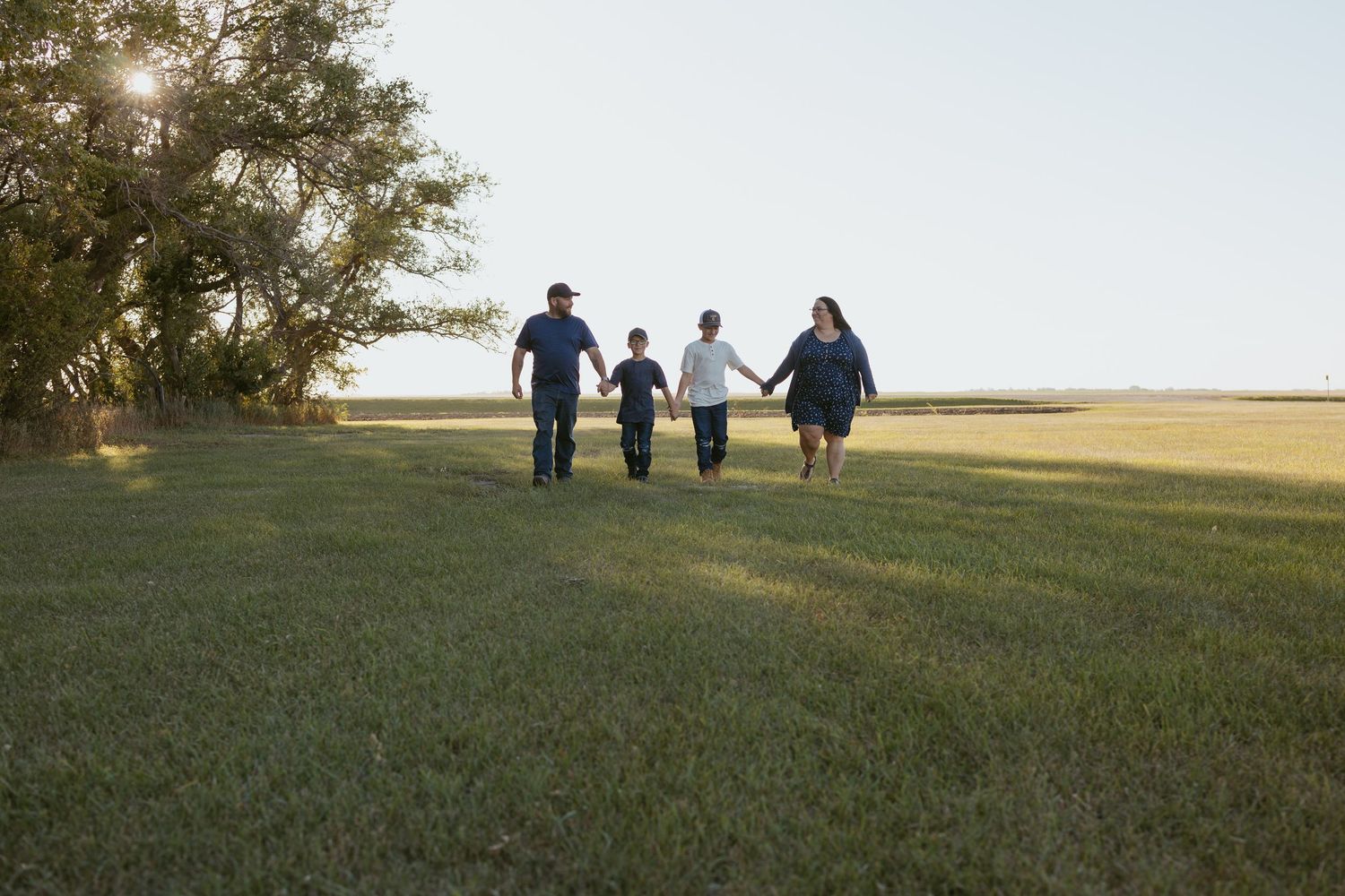 Group walking together across a vast grassy field at sunset.