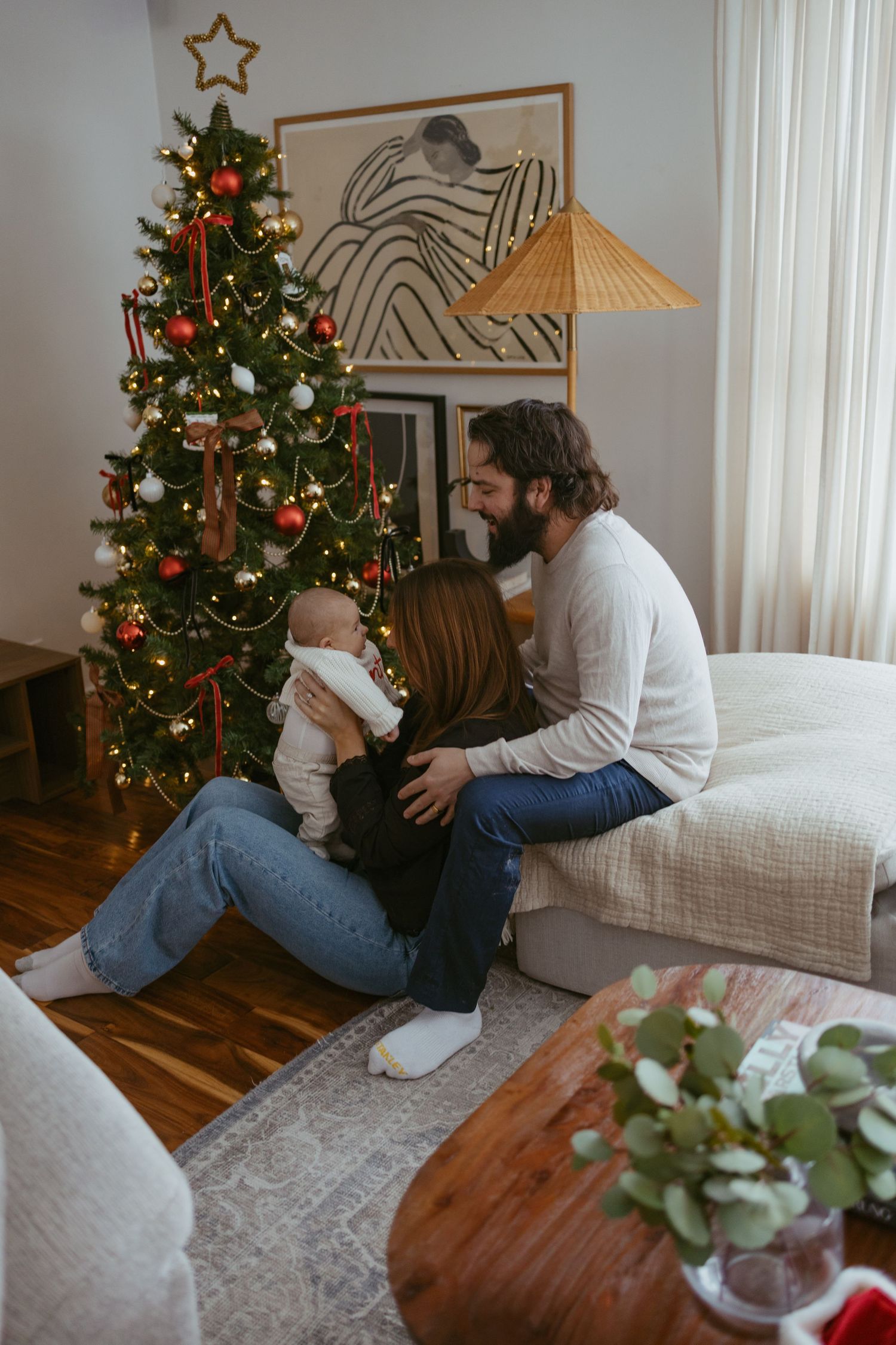 Living room decorated for Christmas with tree and family spending time together on couch.