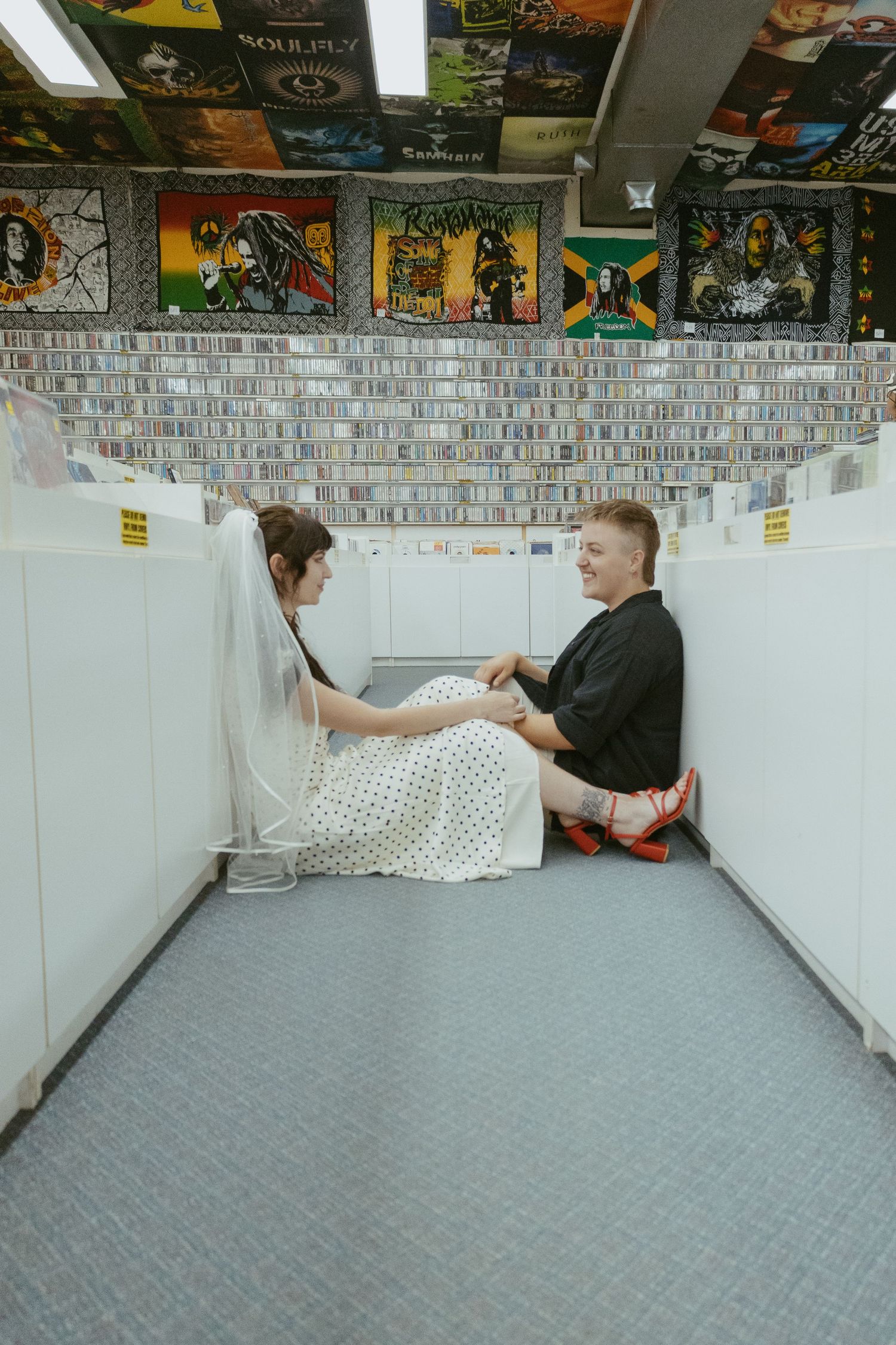 People browsing through vinyl records in a music store with posters on the walls.