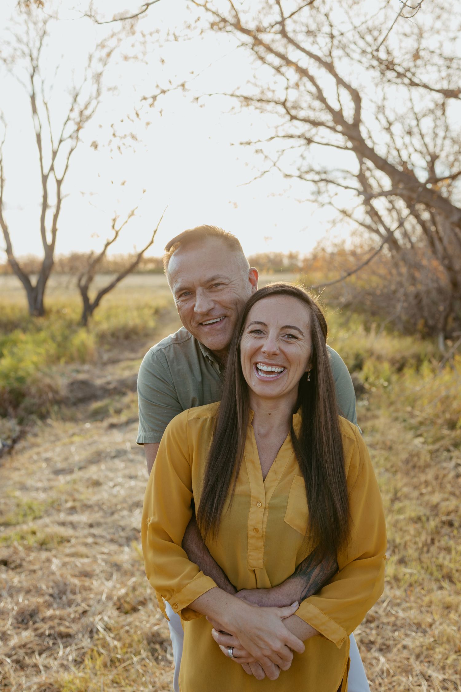 A joyful moment shared between two people in a sunlit field during autumn.
