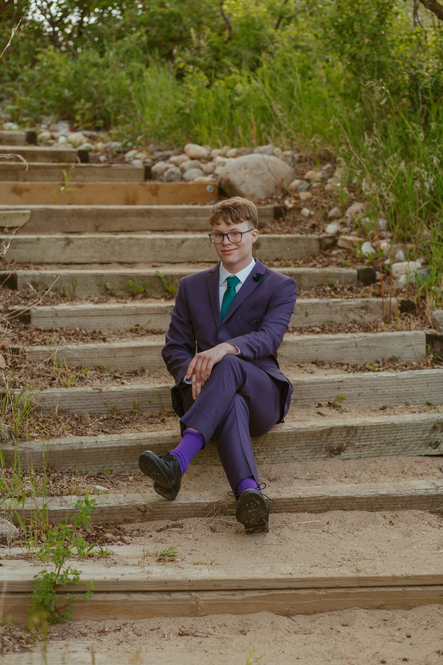 Formal portrait series on concrete steps showing someone in a navy suit and green tie.