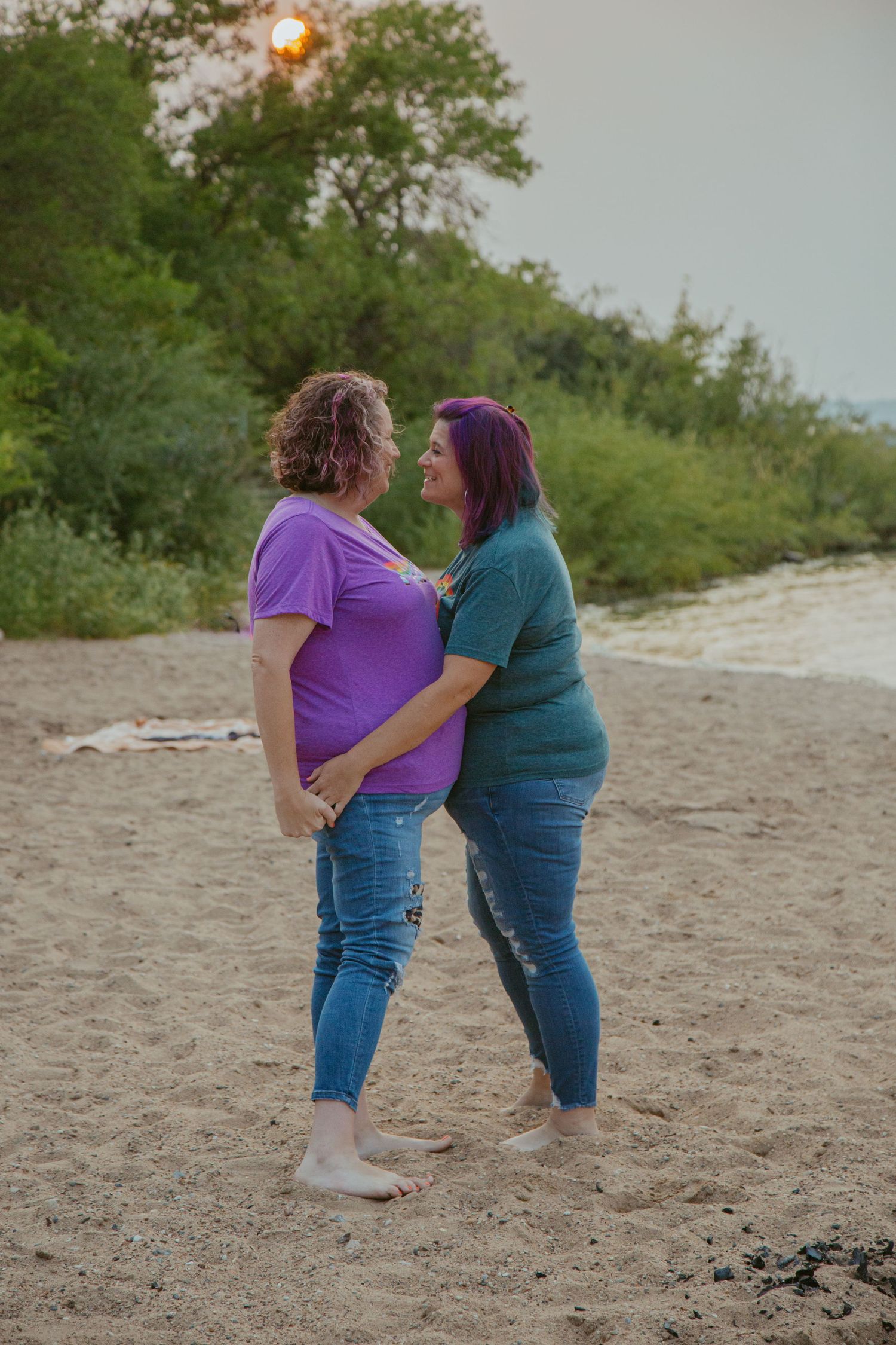 Two people playing and laughing together on a beach.