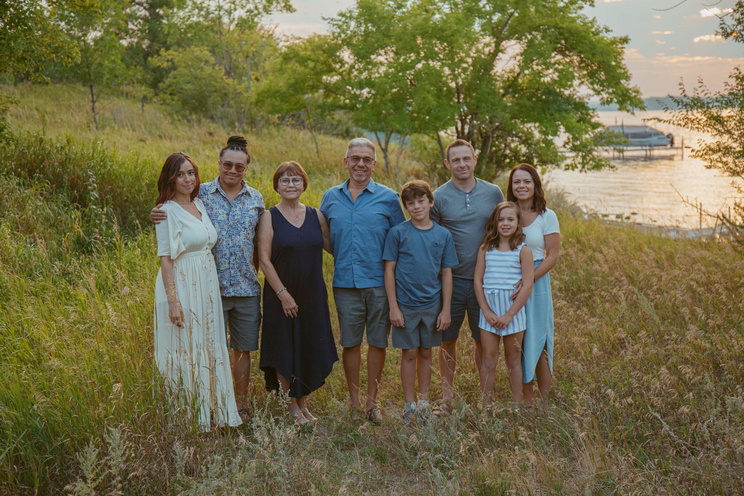 People gather outdoors in casual attire against a natural landscape during sunset.