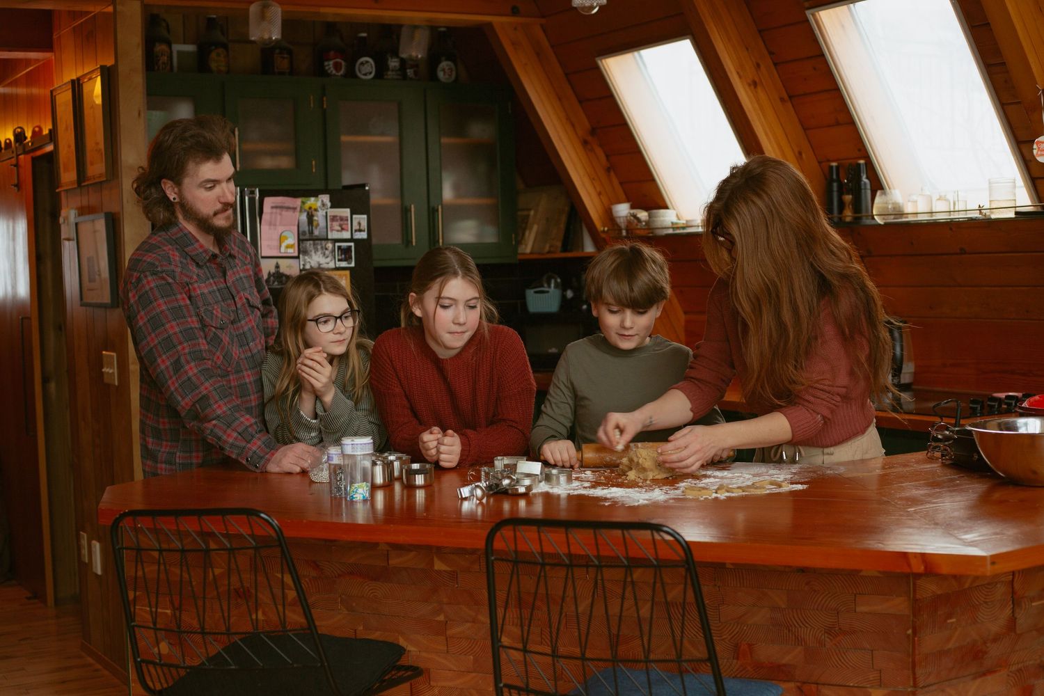 Group gathered around a wooden table playing cards in warm lighting.