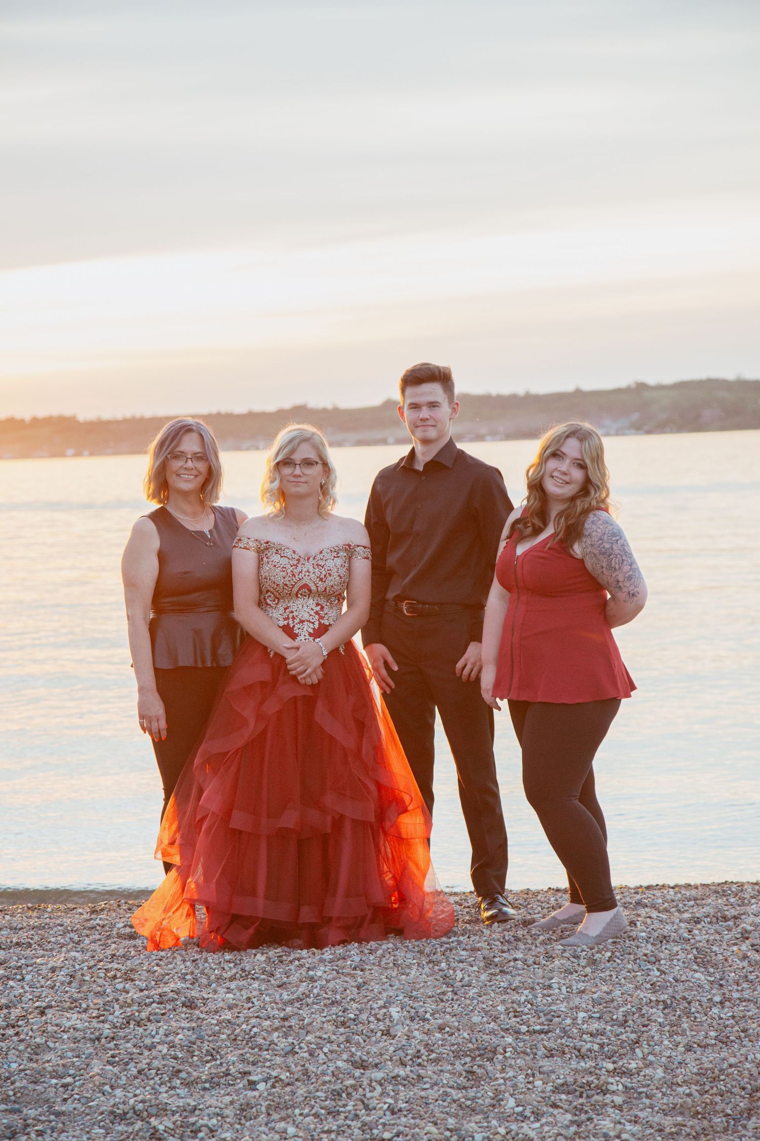 Group portrait at sunset on rocky beach with formal attire.