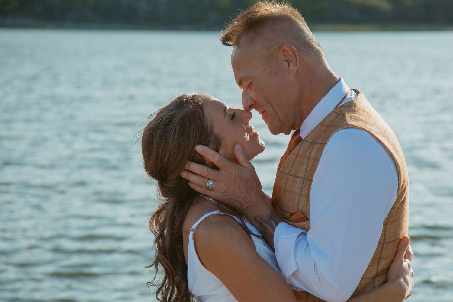 Romantic couple shares intimate moment by lakeside at sunset.