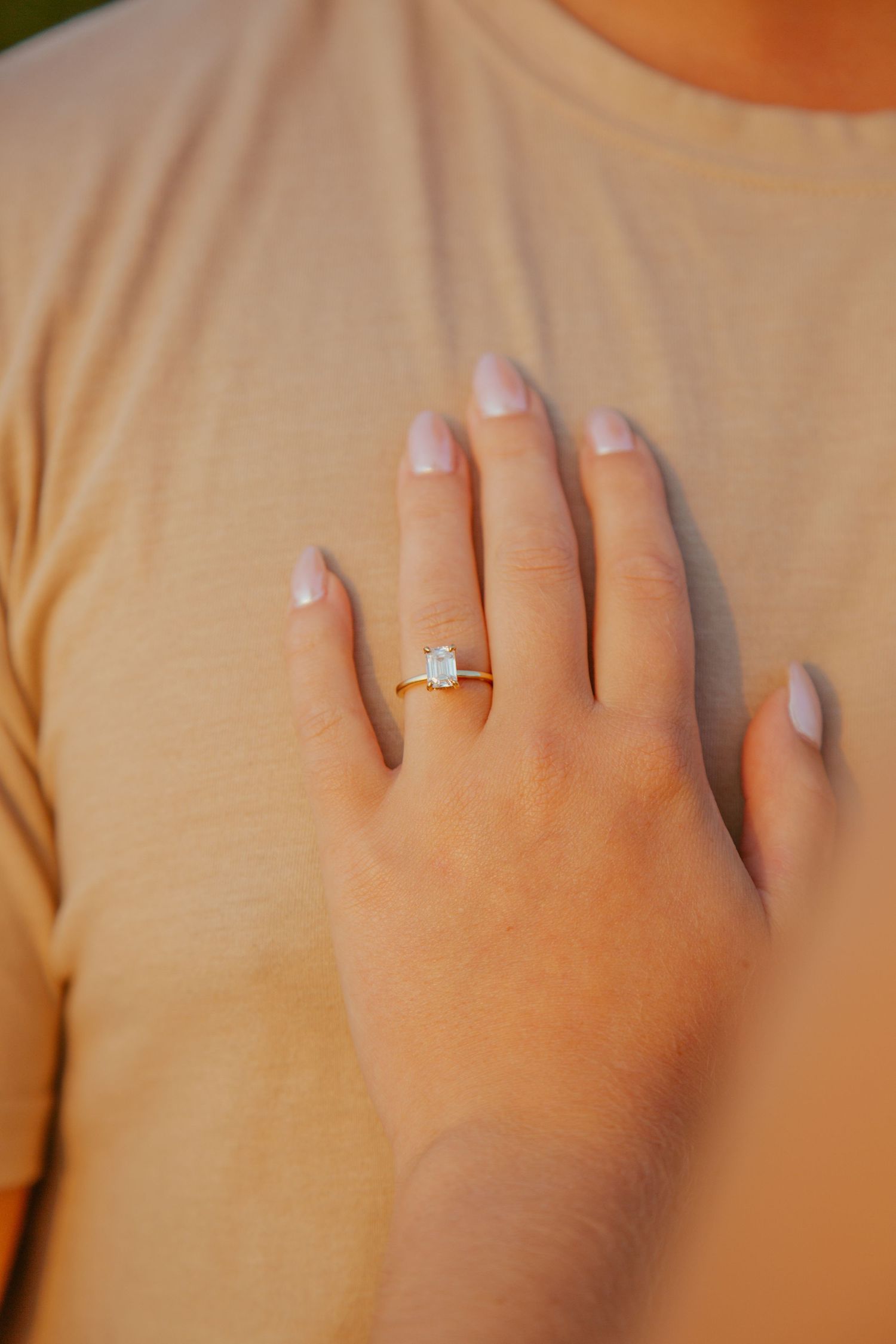 Close-up sequence of hands wearing an engagement ring against a beige background.
