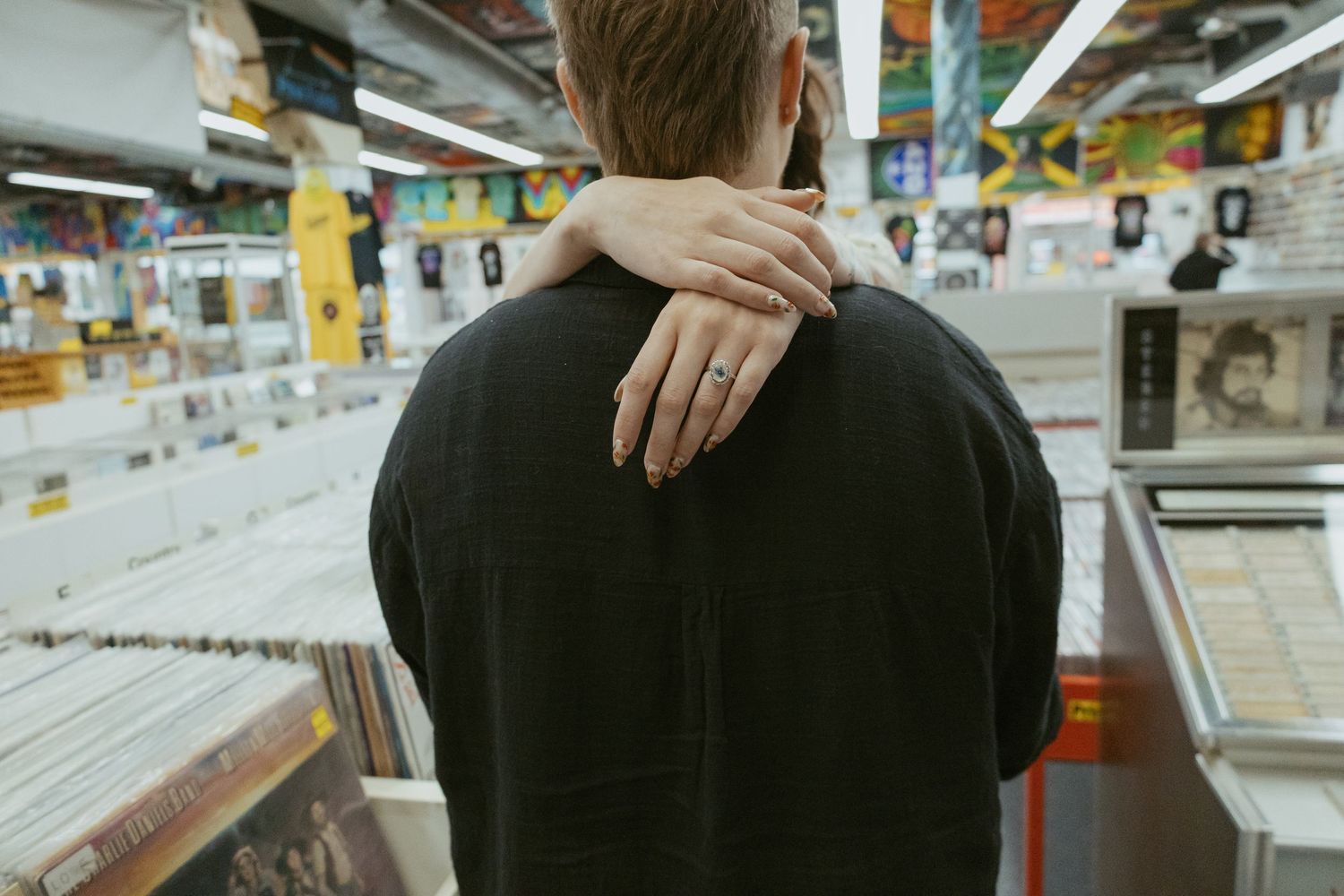 A couple browses through albums in a music store with yellow walls.