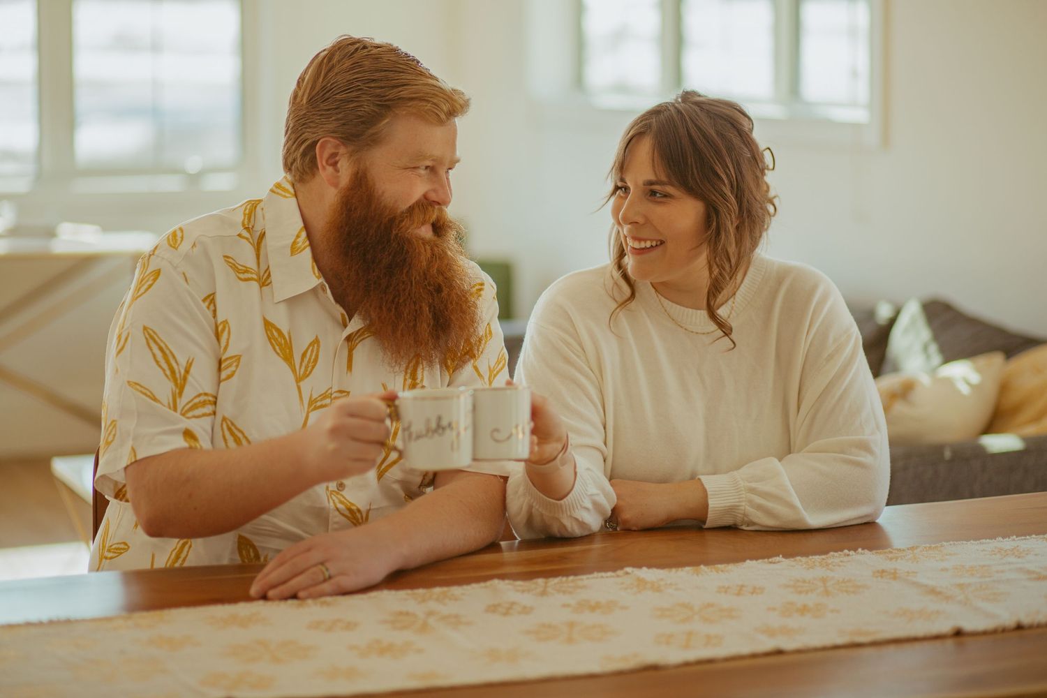 Couple enjoying coffee together at a wooden counter in warm natural lighting.