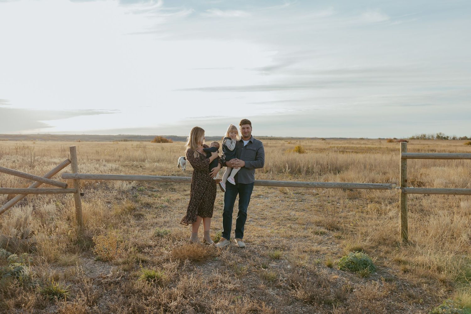 People enjoying views of a scenic grassland landscape with wooden fence posts.