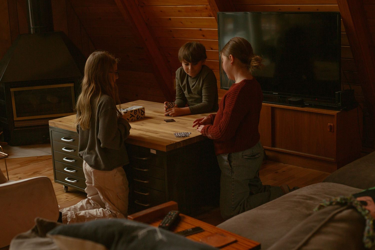 Multiple people engaged in a card game at a wooden dining table.
