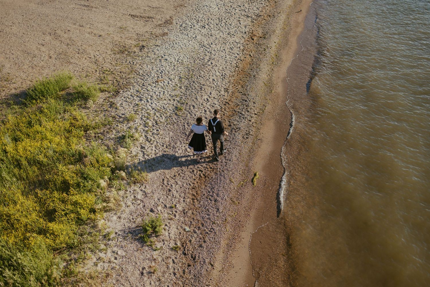 Aerial view of a rocky shoreline with people walking along the water's edge.
