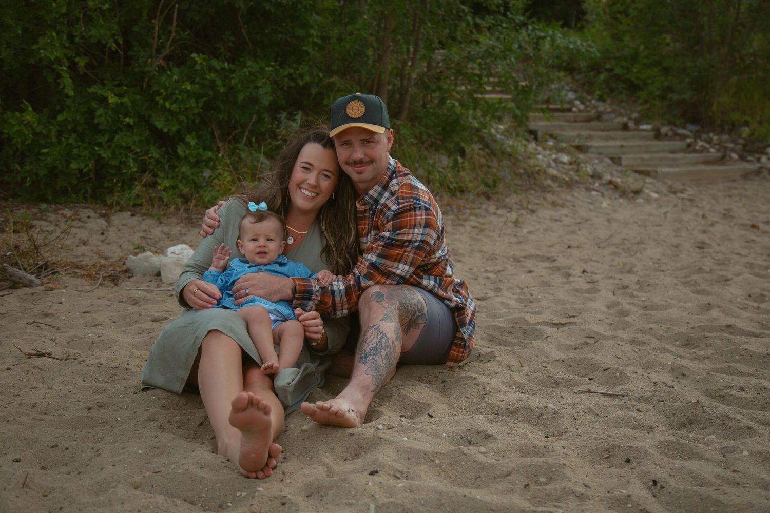 Family enjoying playful moments on sandy beach near water.