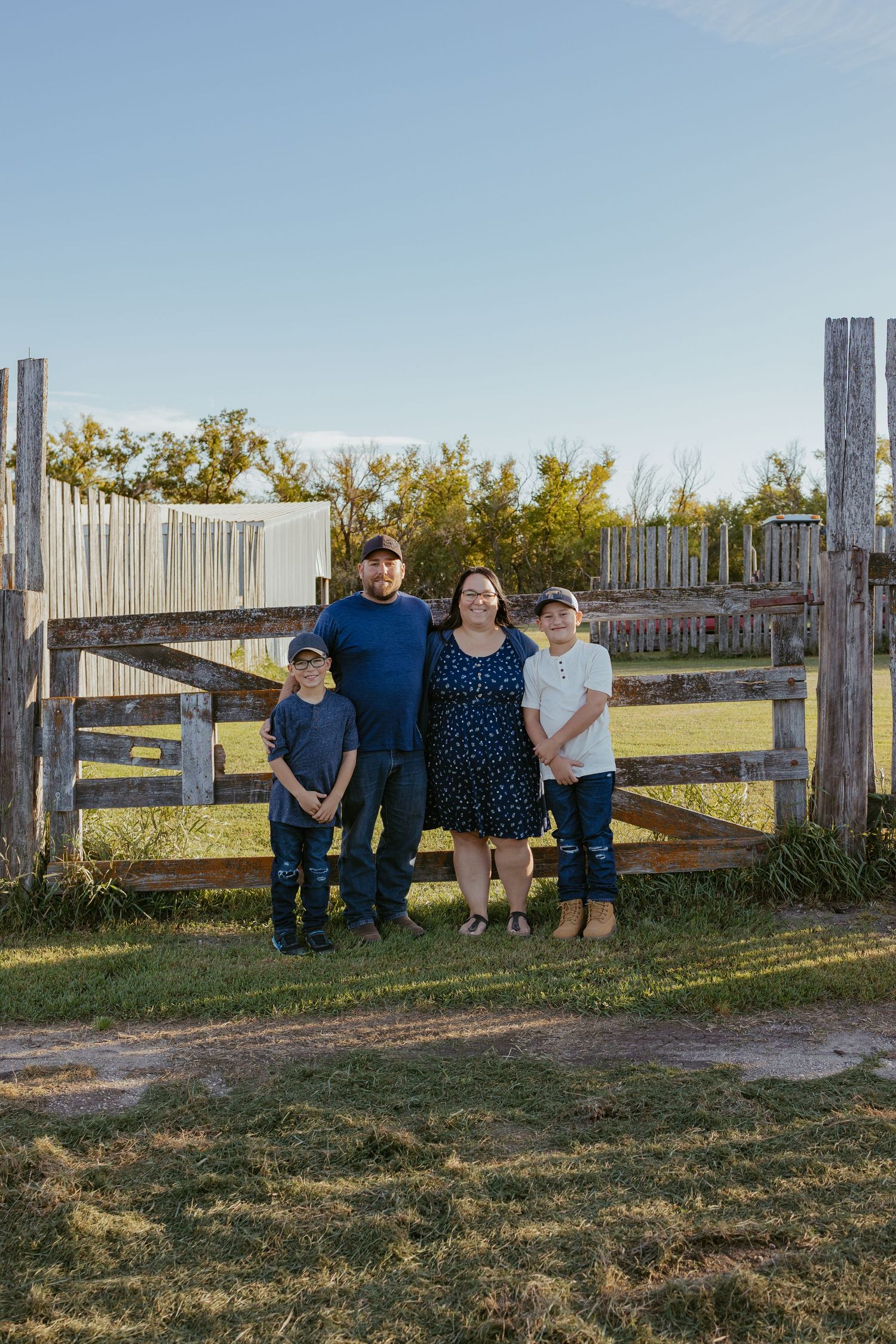 Group poses casually by rustic wooden fence in late afternoon sunlight.