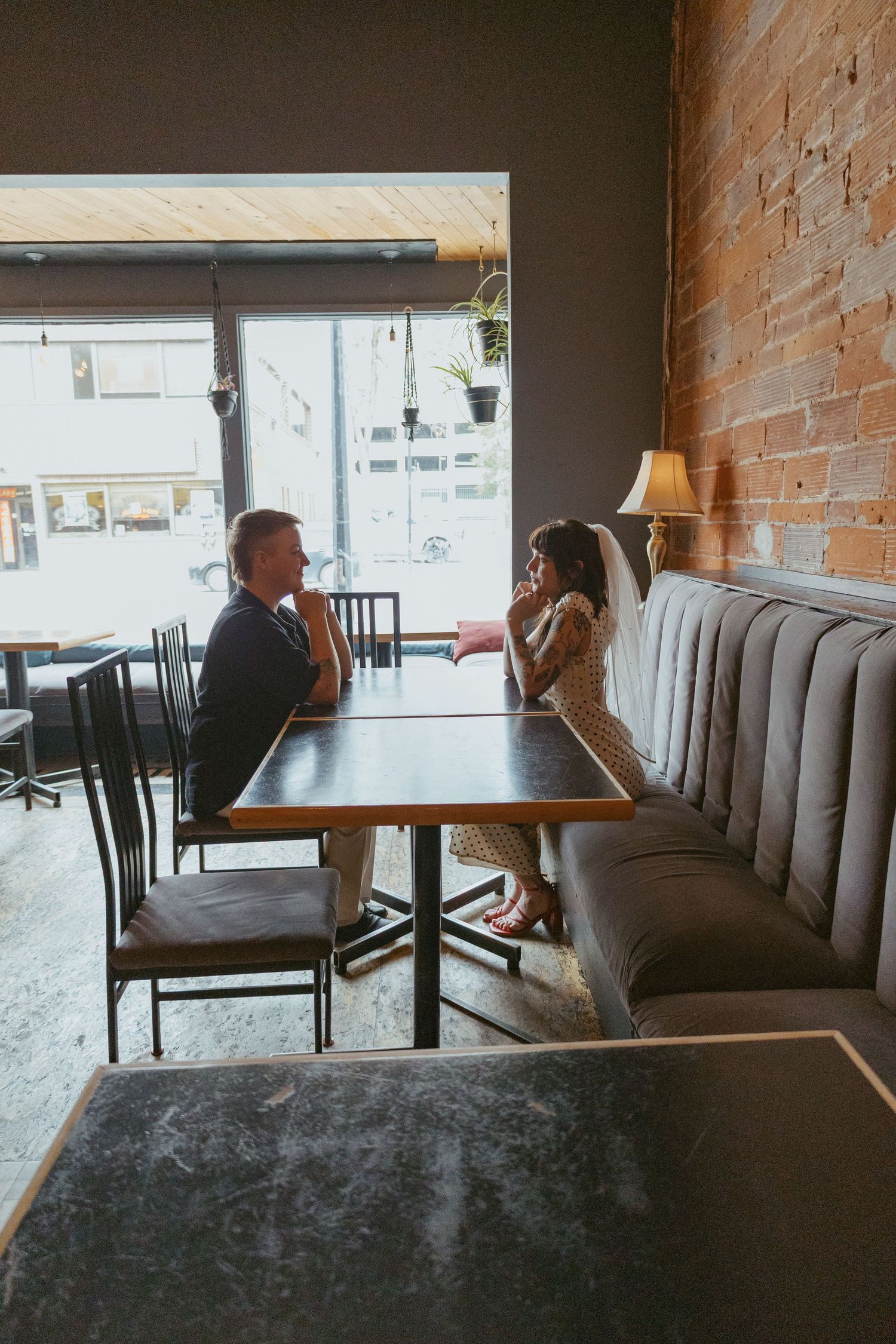 Industrial-style cafe interior with exposed brick walls and cushioned bench seating.