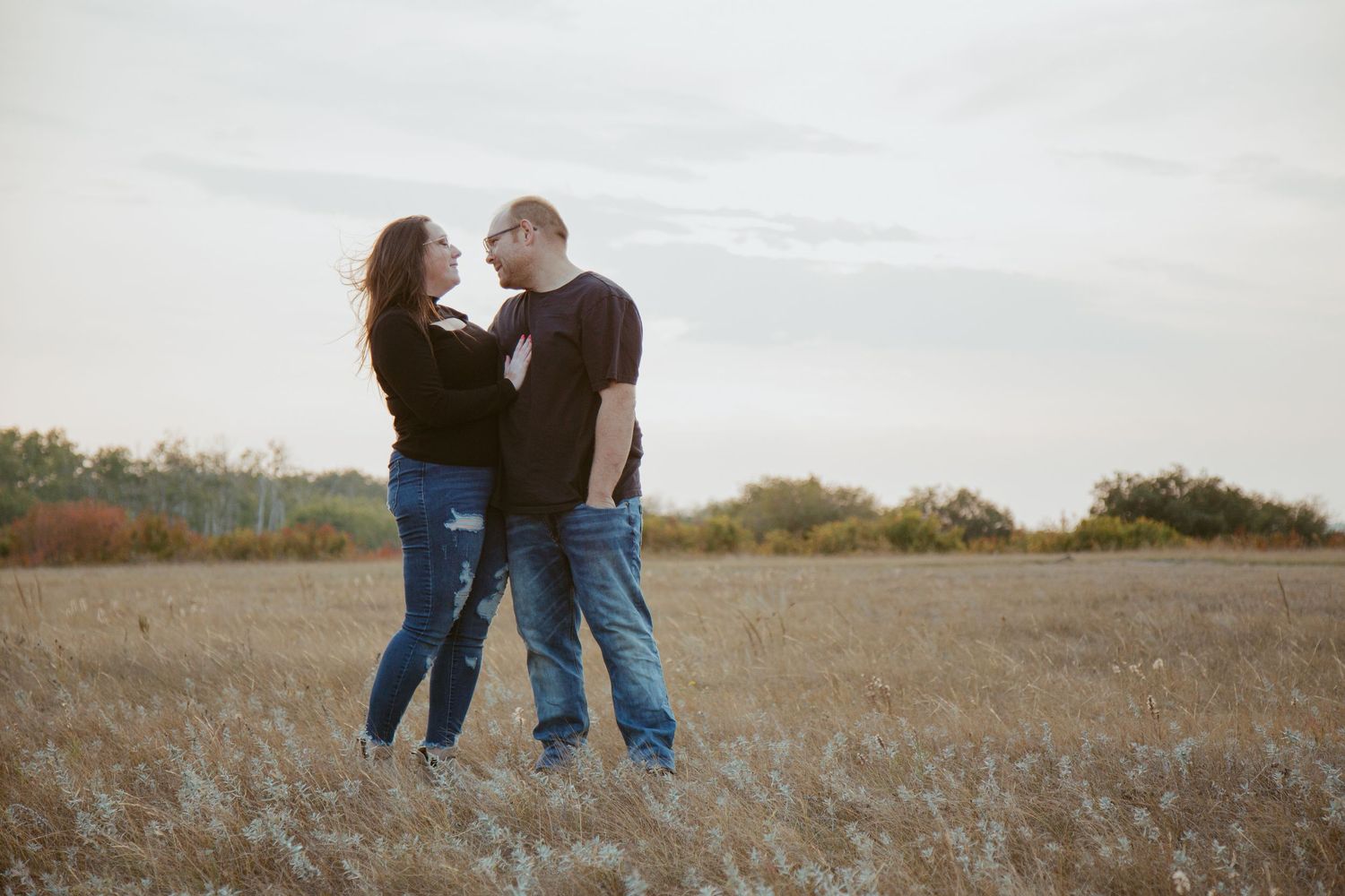 Couple walking together in a vast autumn field at sunset.