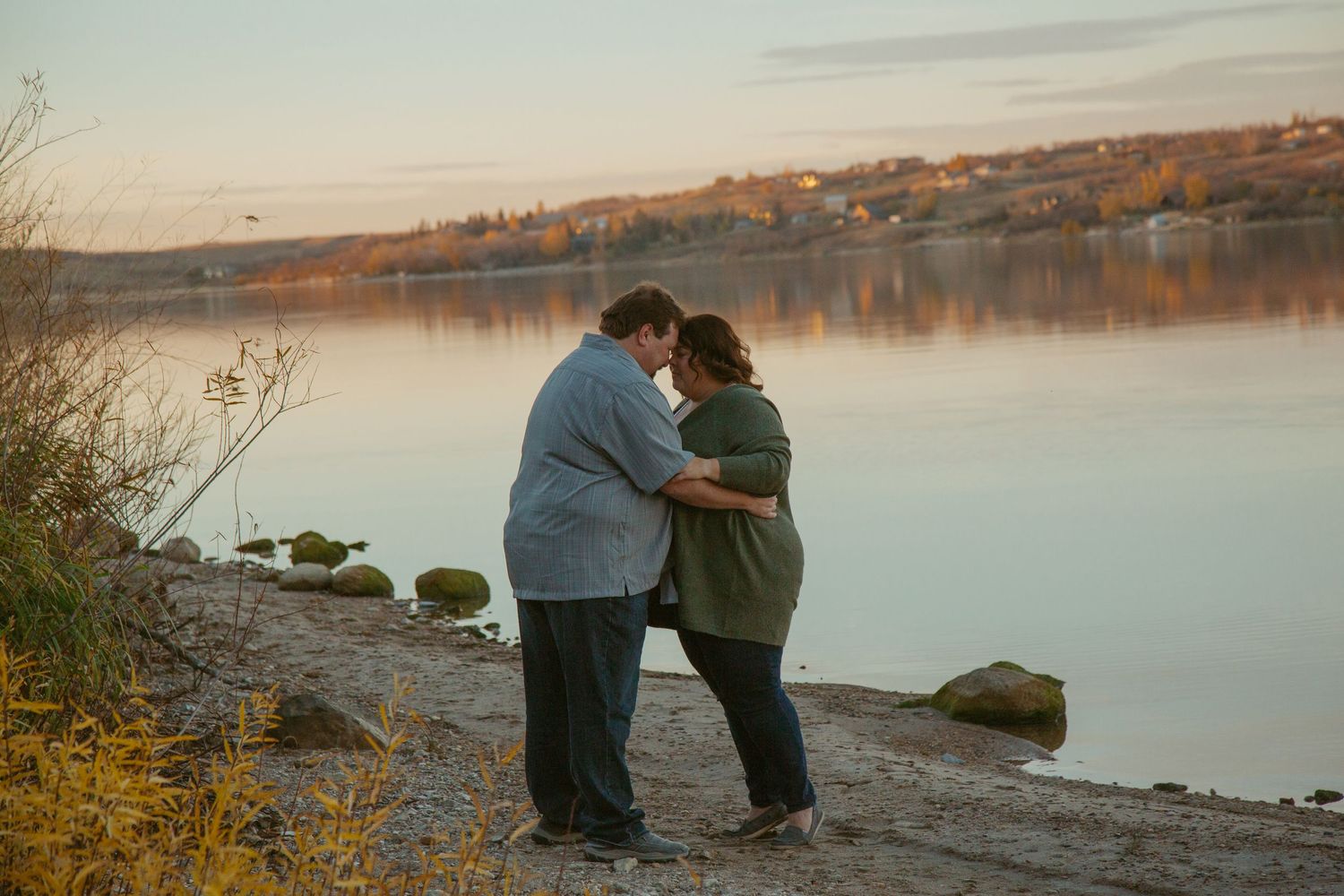Couple embracing at sunset by a serene lakeside.