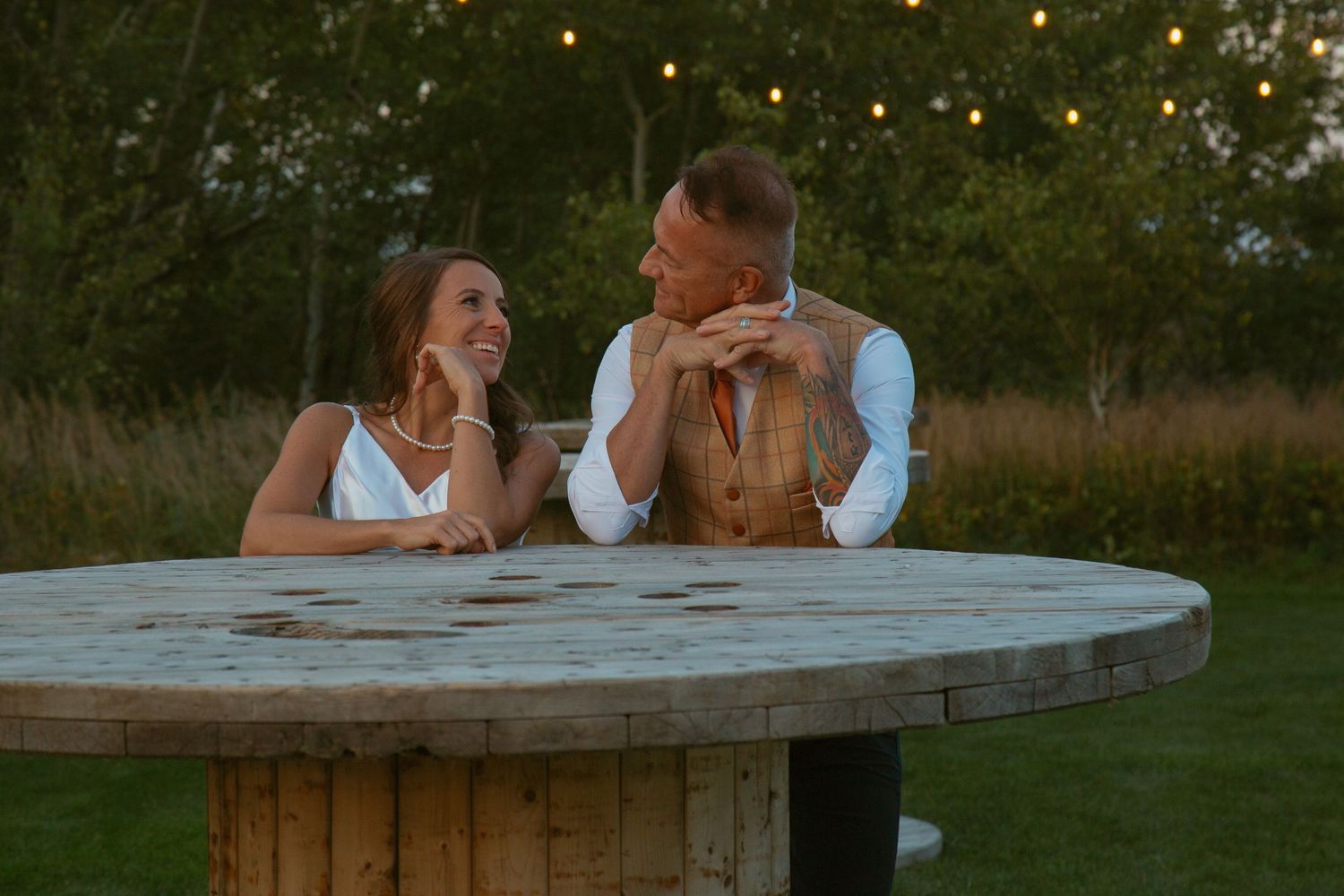 Couple relaxes at a curved stone bench in an outdoor garden setting.