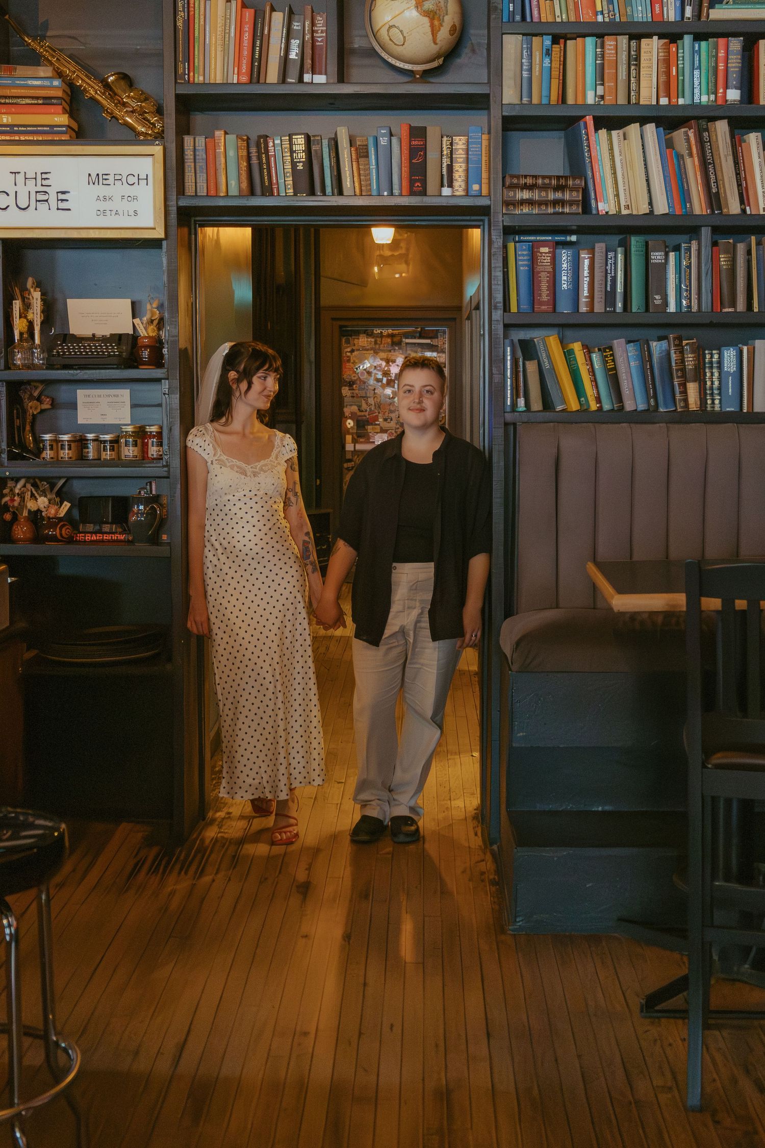 Library-themed bar interior with wooden floors and floor-to-ceiling bookshelves.